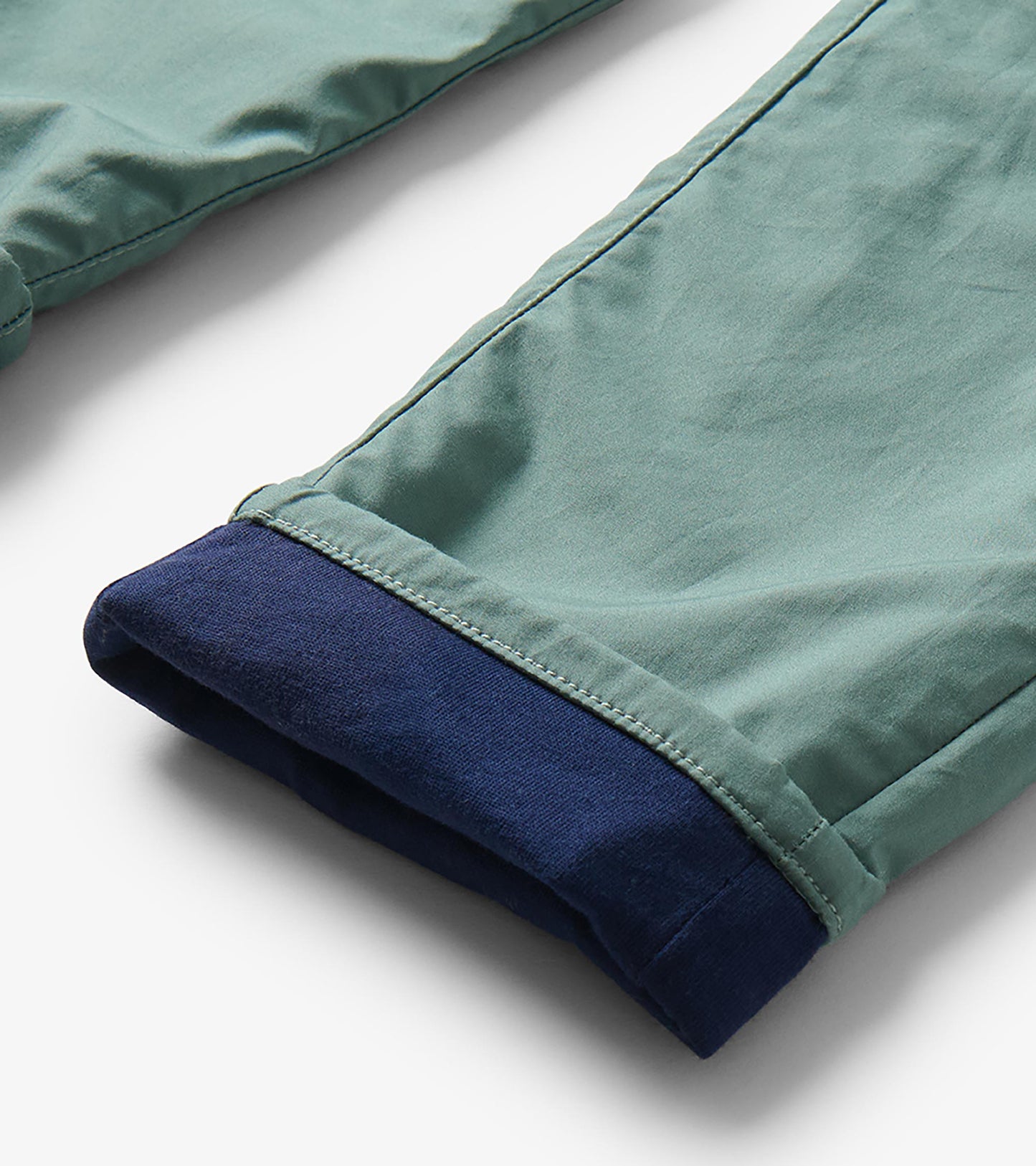 Close-up of green pant cuff rolled to reveal navy lining