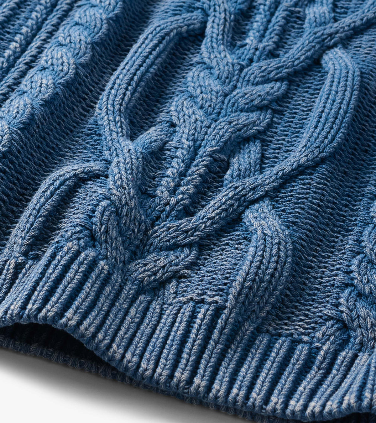 Close-up of stellar blue cable knit pattern with ribbed hem