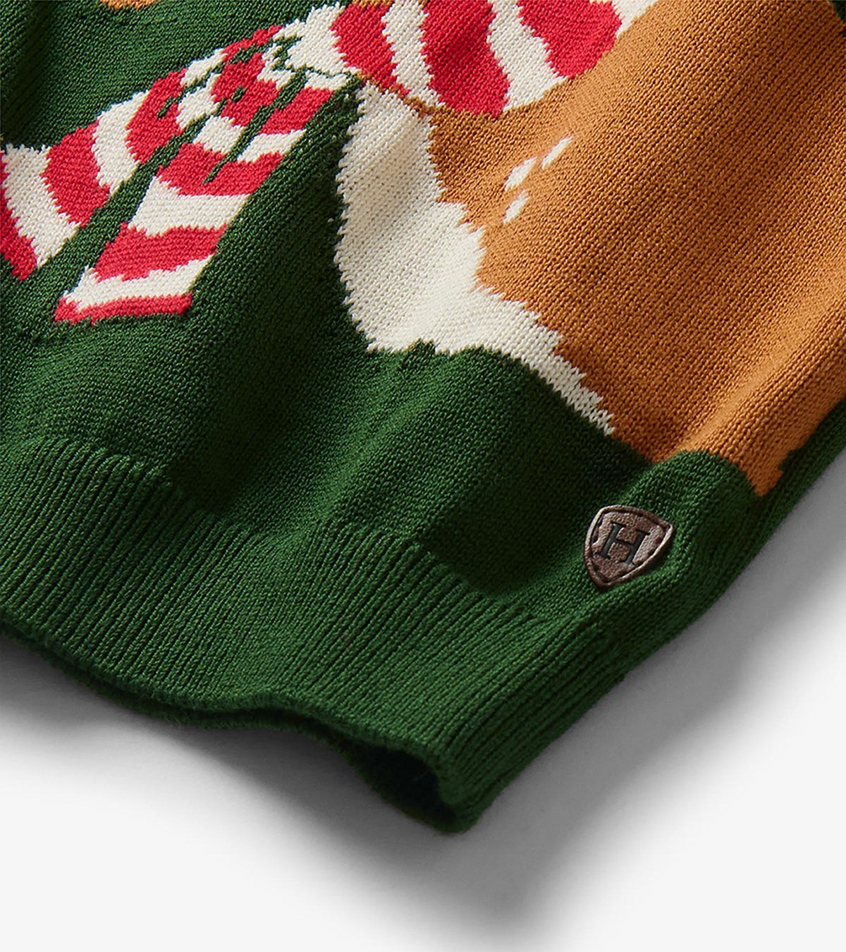 Close-up of sweater hem with reindeer graphic detail, red and white striped scarf, and small Hatley badge