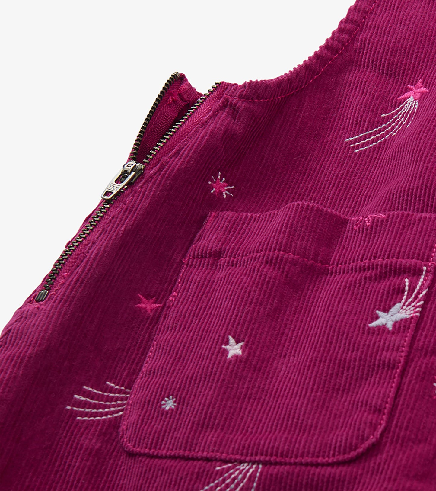 Close-up of berry pinafore dress showing side zipper, front pocket, and star embroidery details