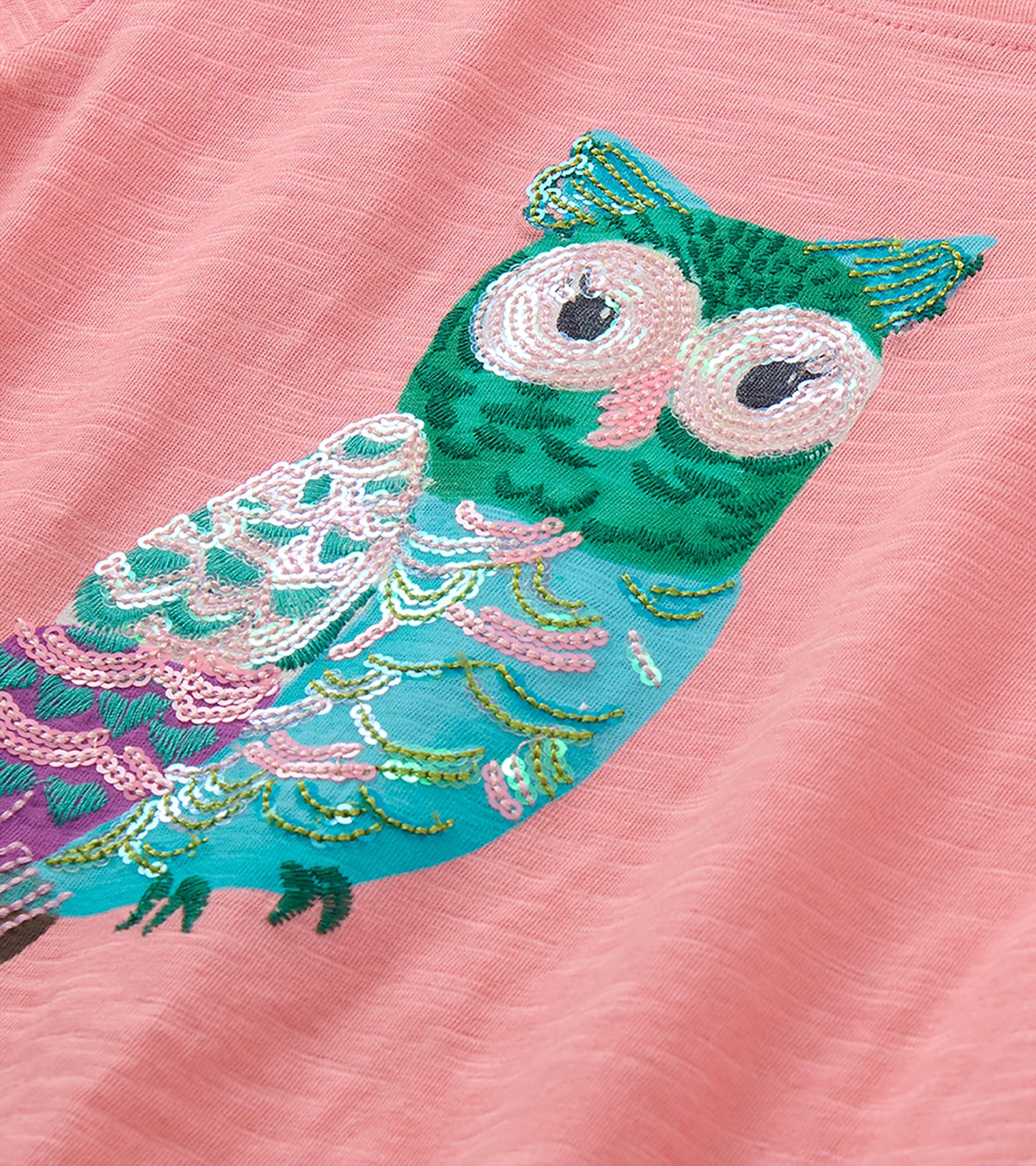 Close-up of multicolor owl graphic with pink sequined details on pink T-shirt