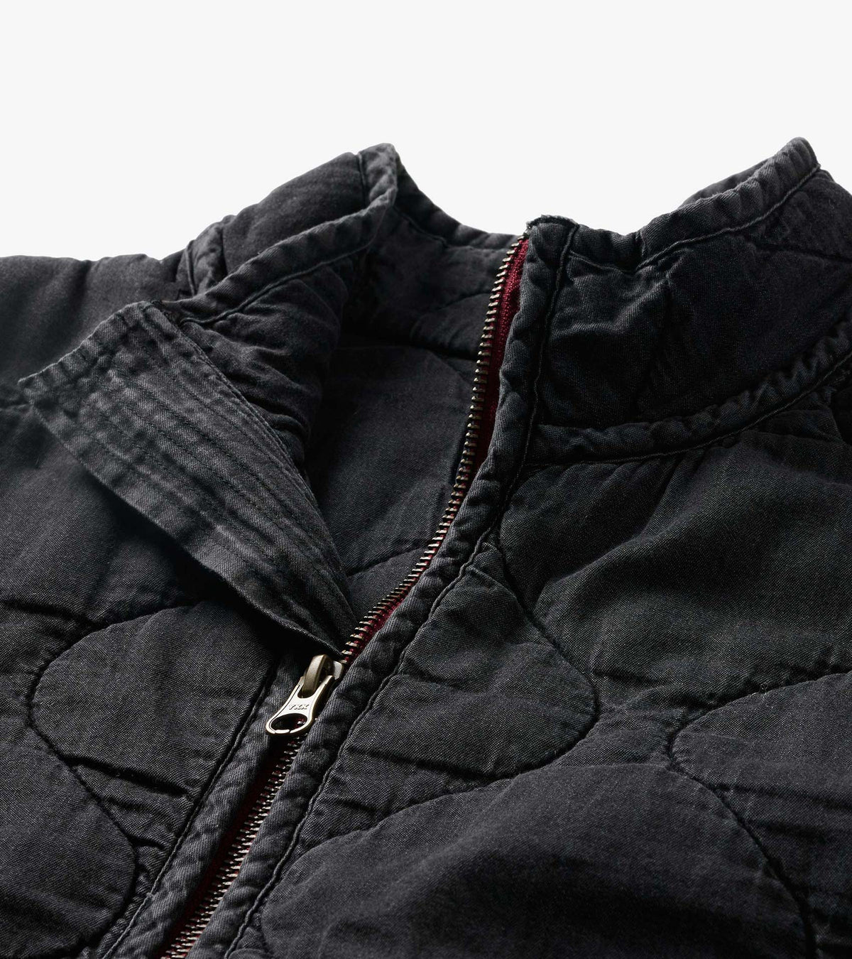 Close-up of washed black quilted jacket collar and silver zipper with burgundy trim