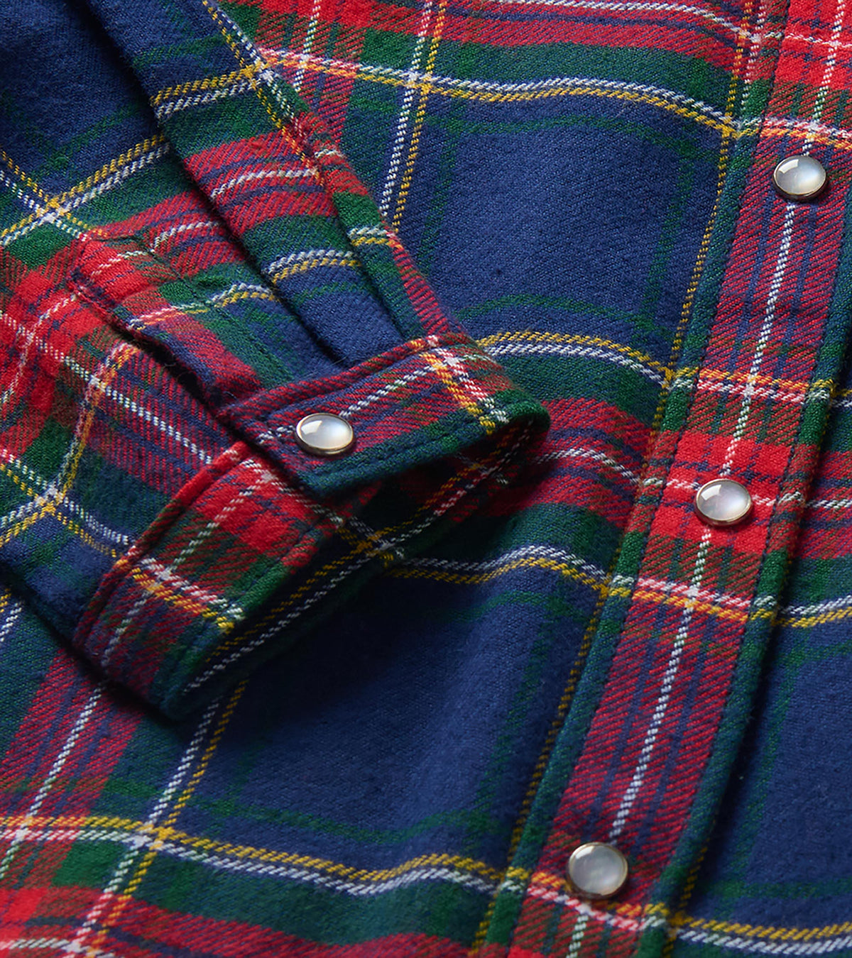 Close-up of navy, red, and green plaid shirt with snap buttons and cuff detail