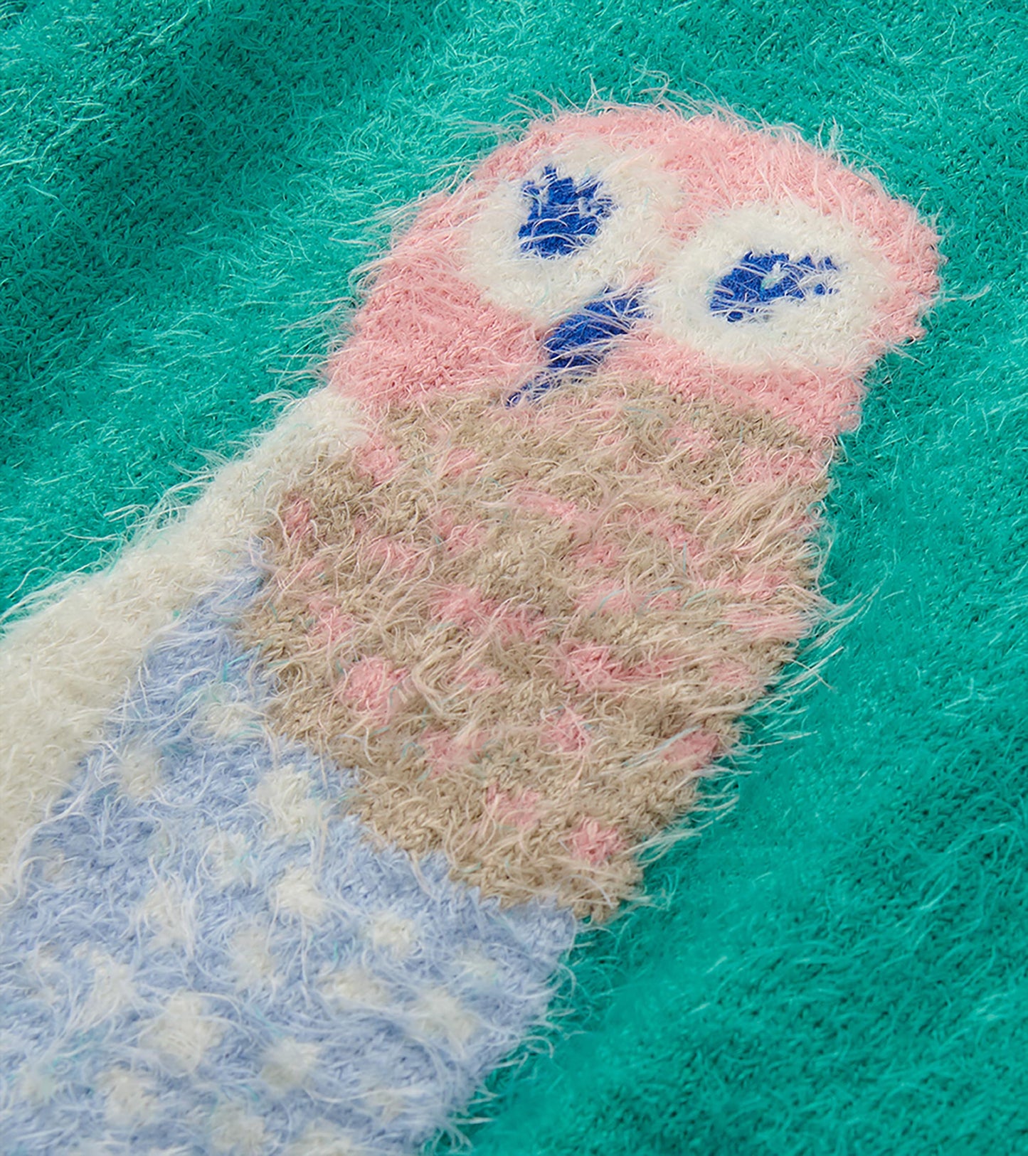Close-up of pastel owl graphic on teal fuzzy sweater