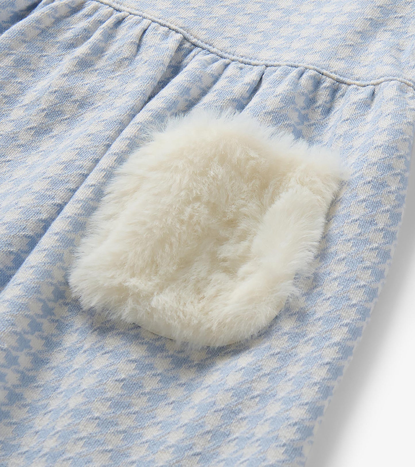 Close-up of white fluffy patch pocket on blue and white houndstooth dress
