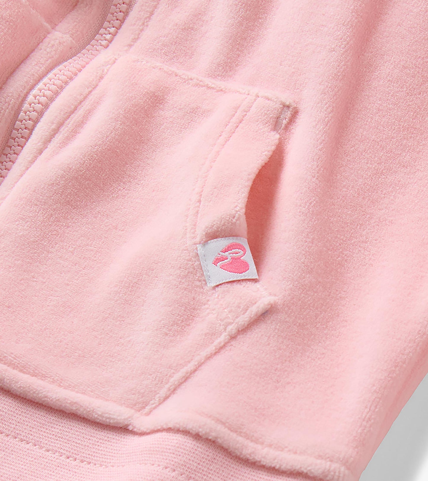 Close-up of orchid pink hoodie showing zipper, kangaroo pocket seam, and small logo tab
