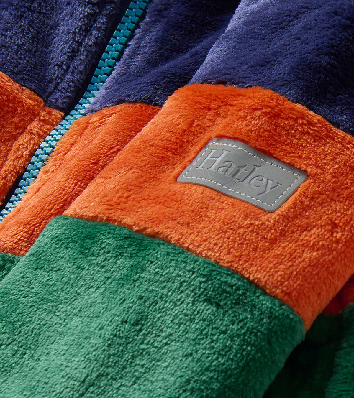 Close-up of blue, orange and green fleece jacket with zip and Hatley sleeve patch