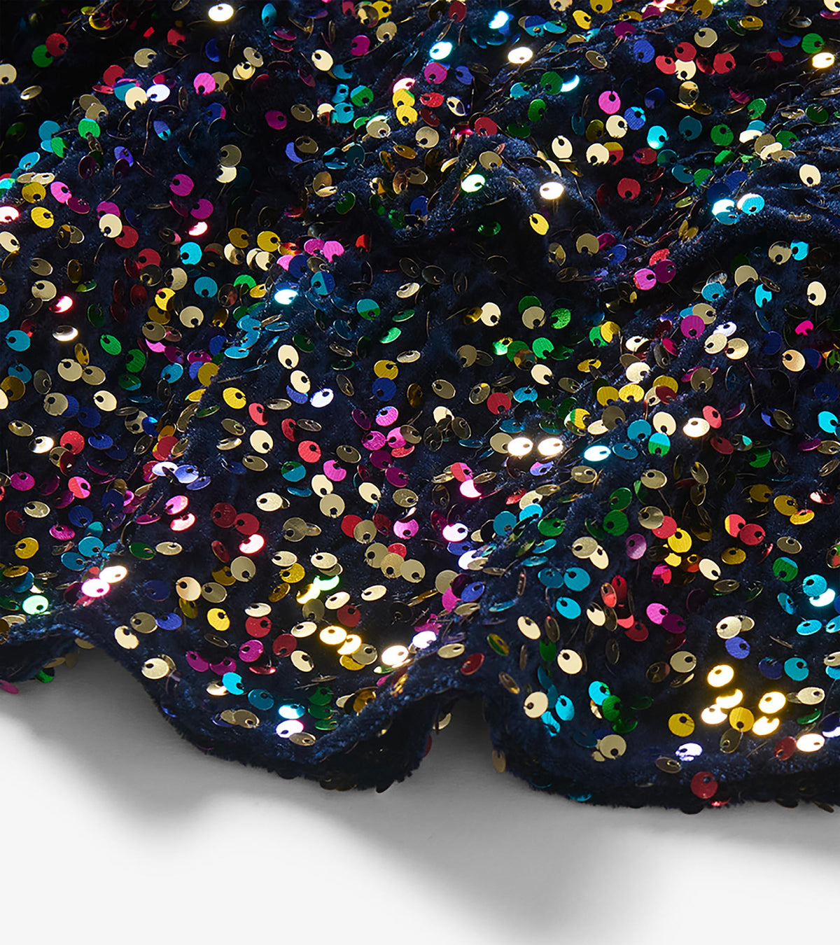 Close-up of navy fabric covered with multicolor sequins on the flounce skirt