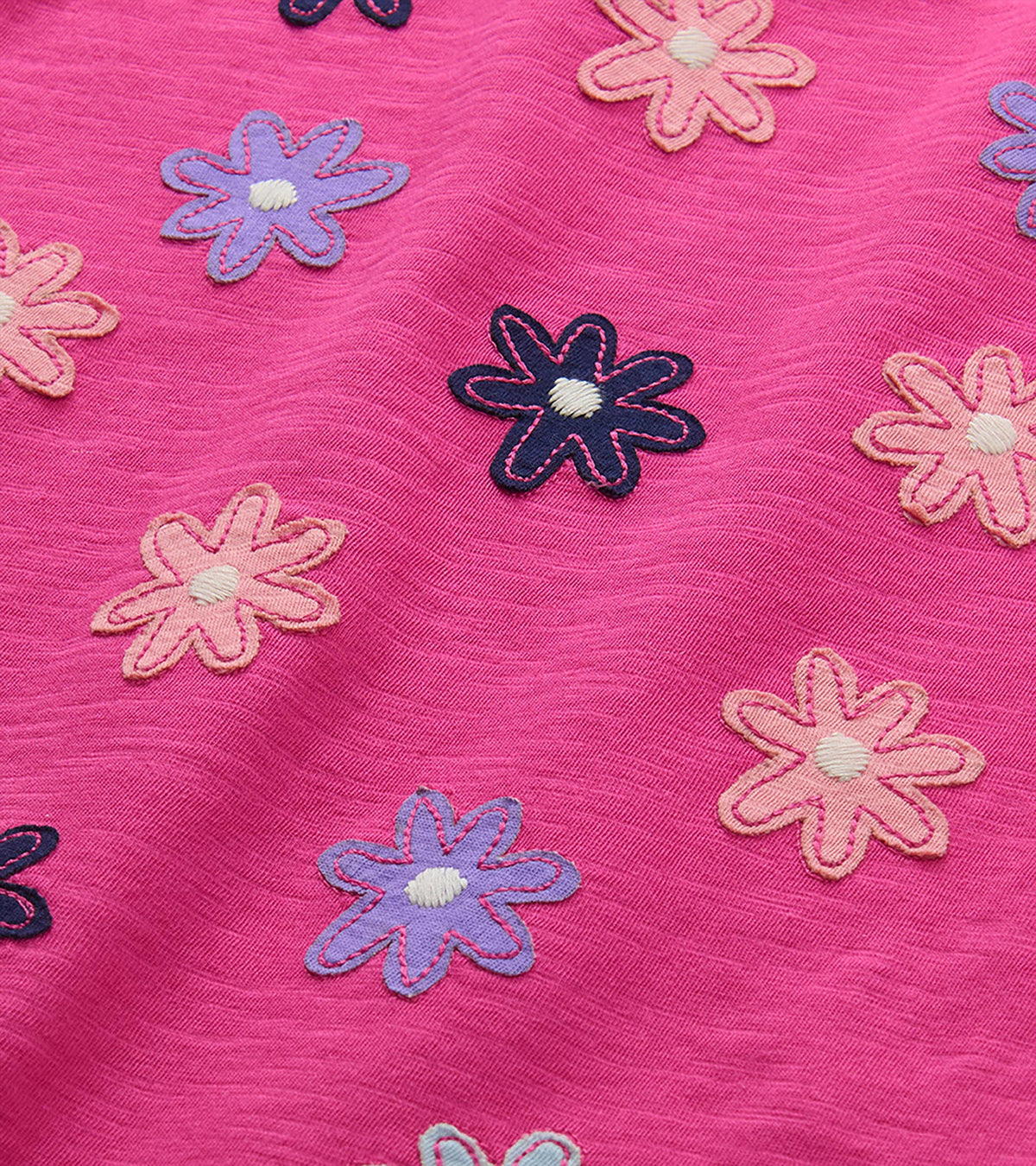 Close-up of pink, purple, and navy flower appliqués on berry pink fabric
