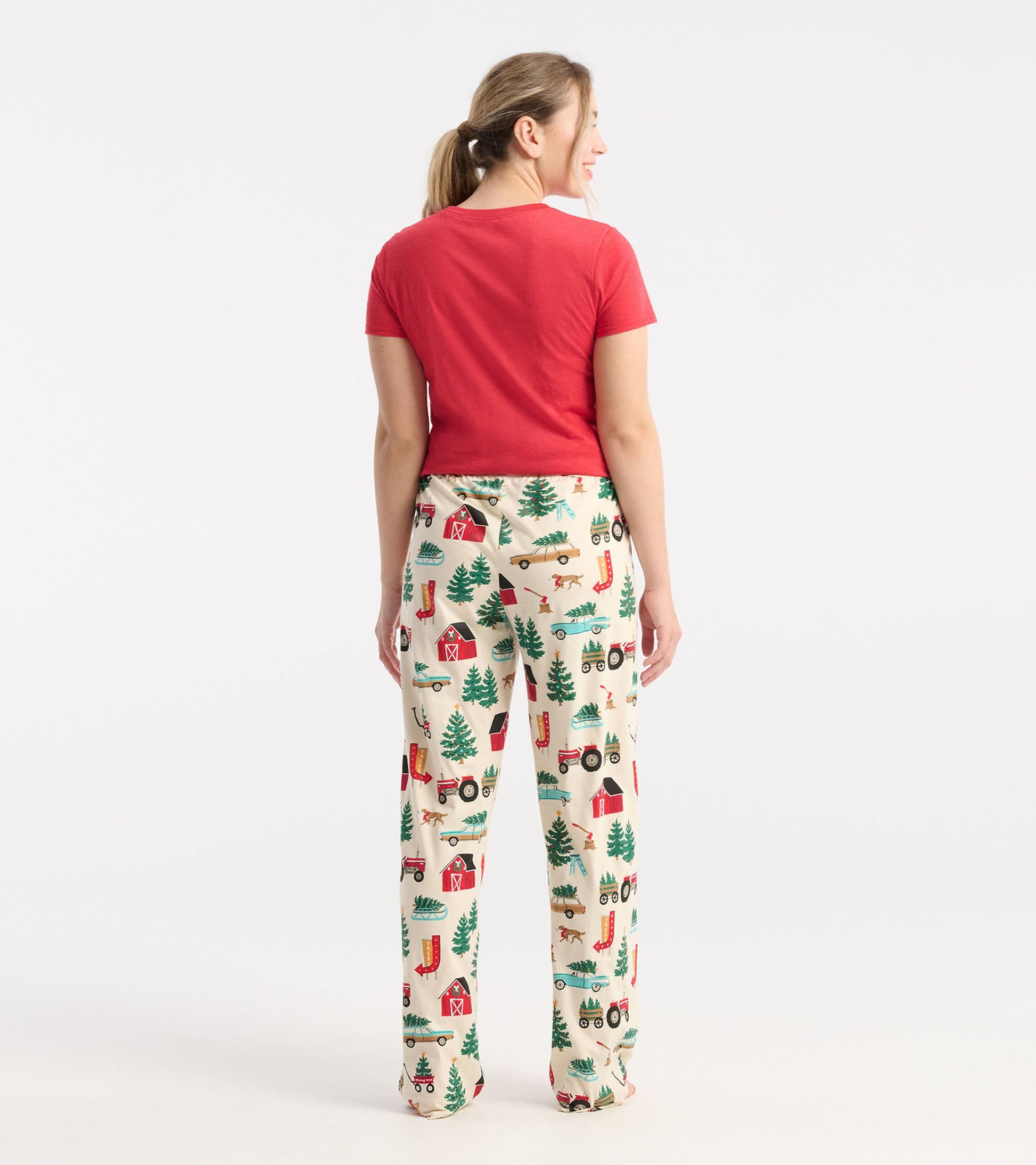 Cream cotton pajama pants featuring a festive Christmas tree farm print with barns, tractors, and trees.