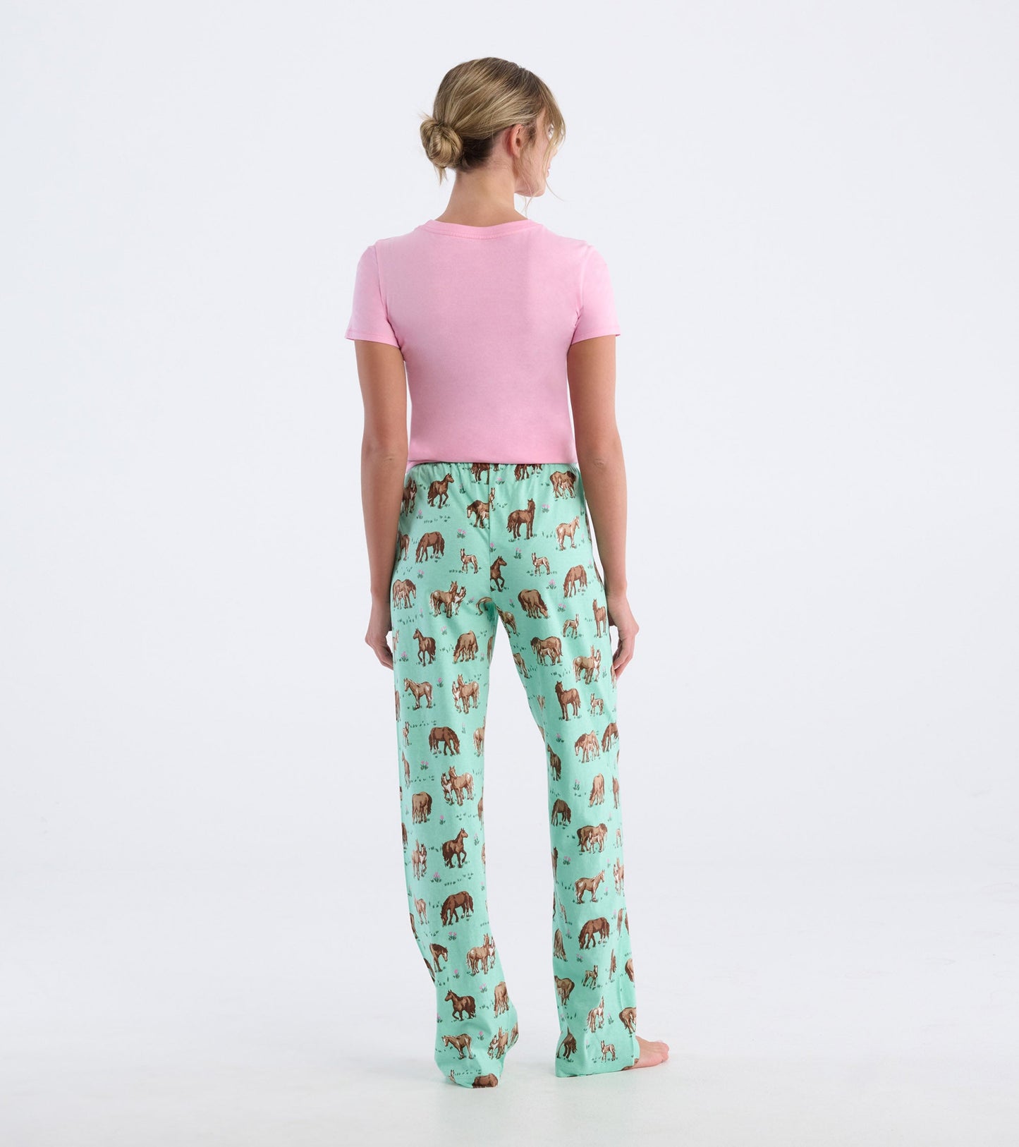 Mint green cotton pajama pants featuring a playful horse print, styled with a fitted pink top, shown from the back.
