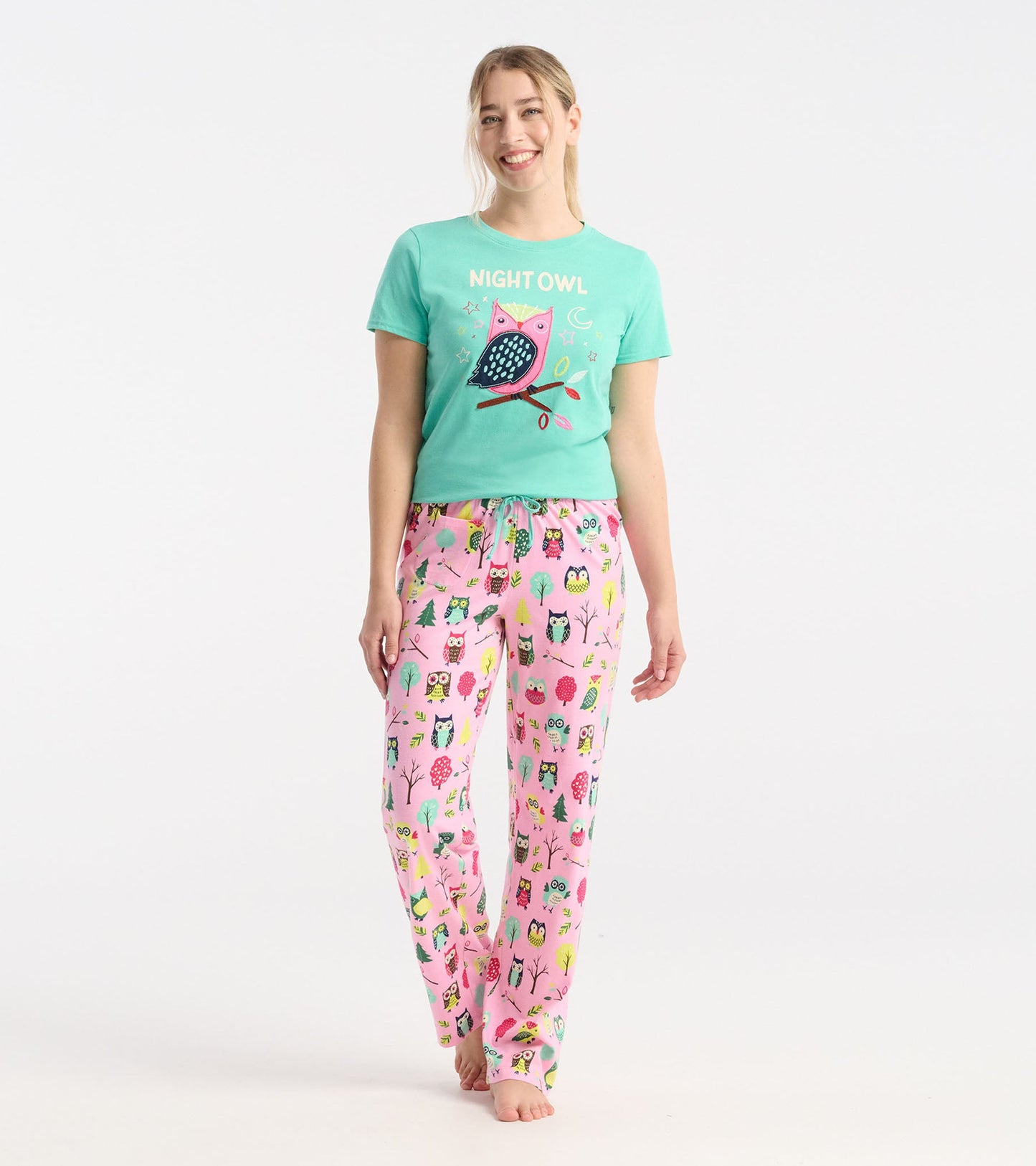 Light pink cotton pajama pants featuring colorful owl and tree patterns, with an elastic waistband and drawstring.