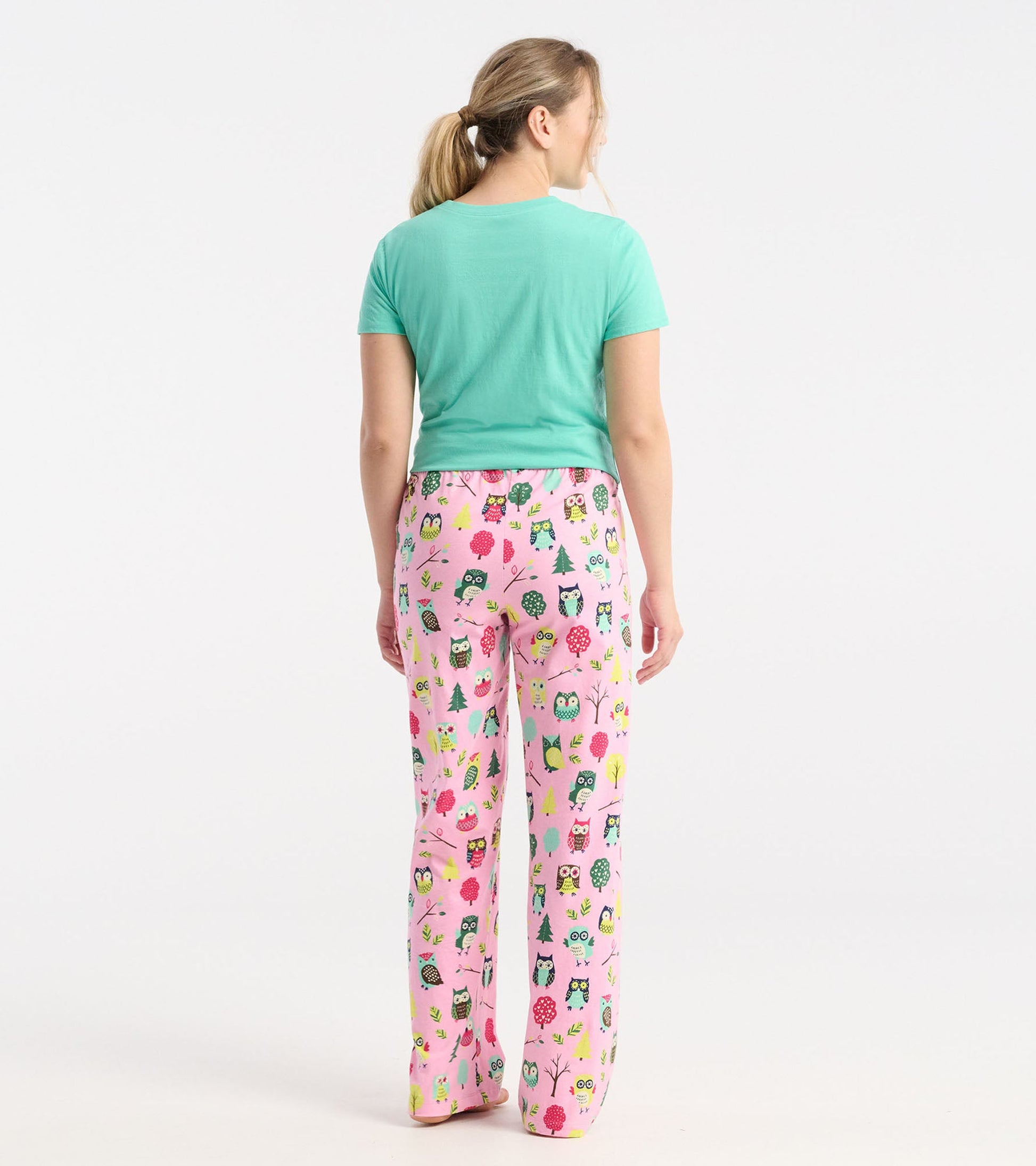 Pink cotton pajama pants featuring a playful owl and tree pattern, styled for comfort and relaxation.