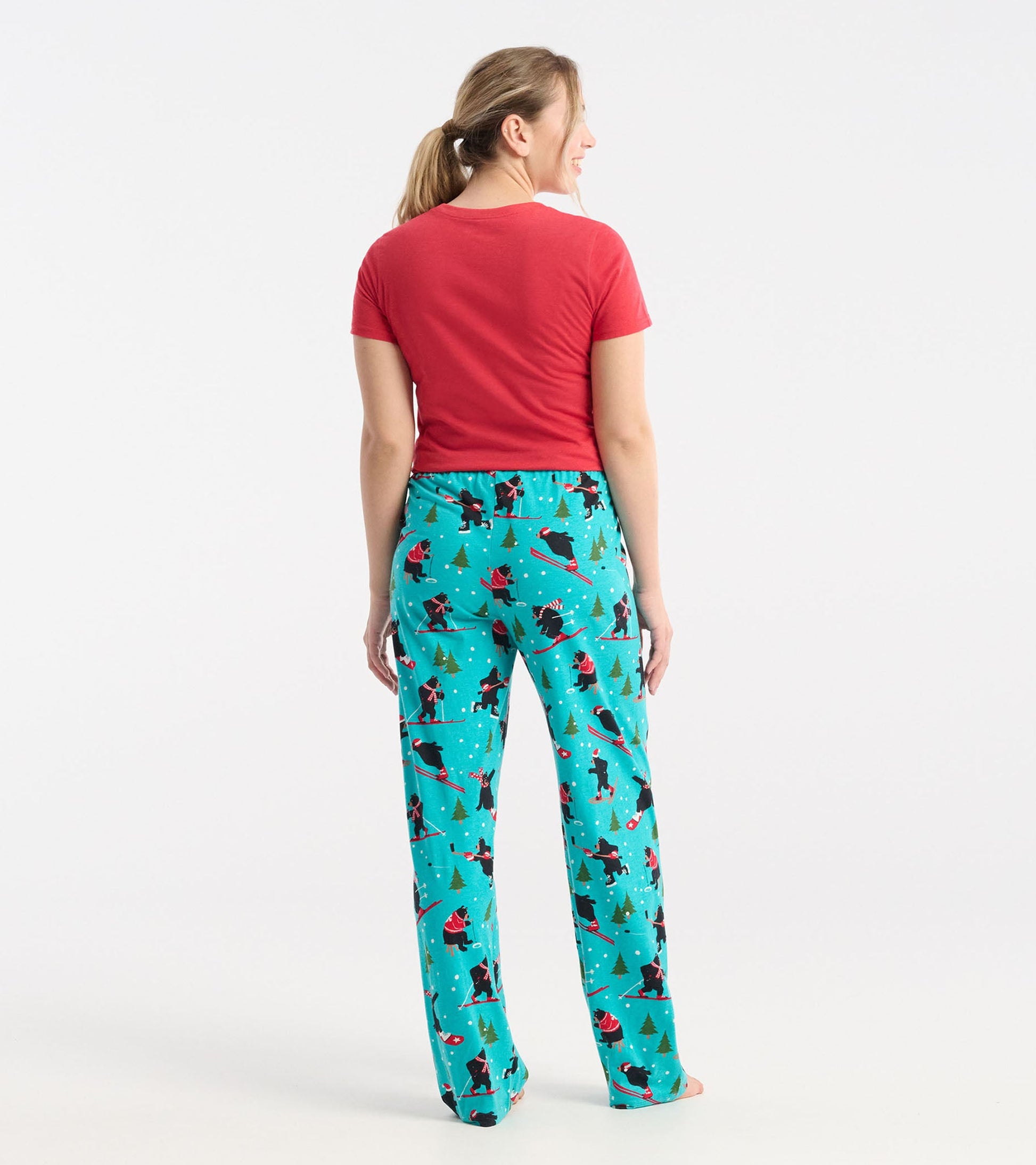 Turquoise cotton pajama pants with a winter sports pattern, featuring skiers and trees, shown from the back.