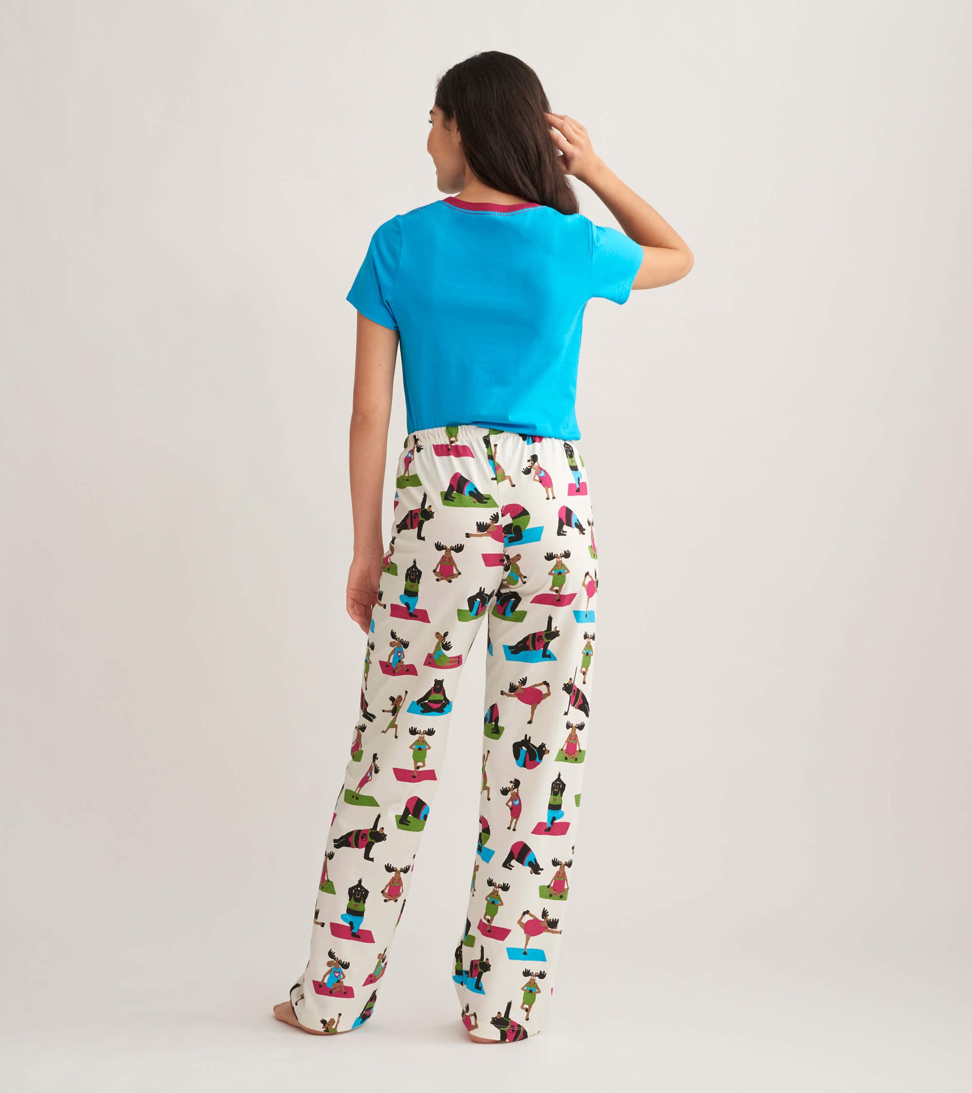 Women's cotton pajama pants featuring a playful yoga bear print on a light background, paired with a blue top.