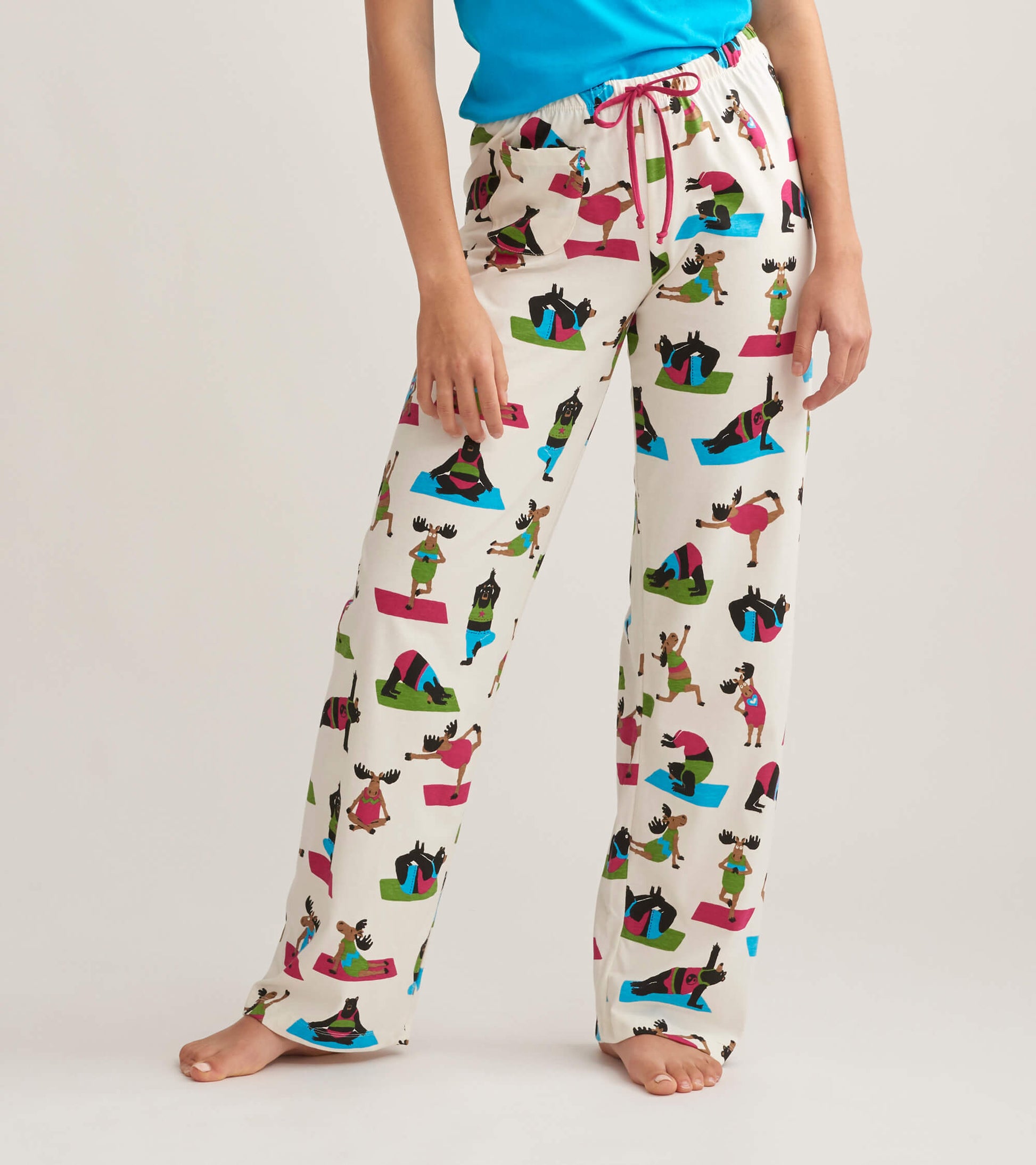 White cotton pajama pants featuring a colorful yoga bear print, with an elastic waistband and drawstring detail.