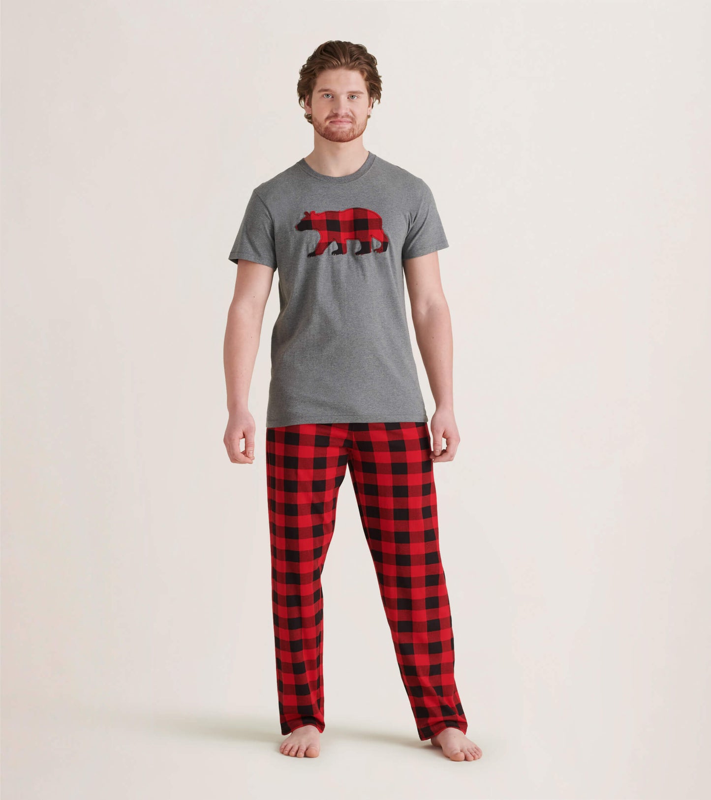 Men's pajama pants in red and black buffalo plaid pattern, made of stretch cotton, worn with a gray t-shirt.