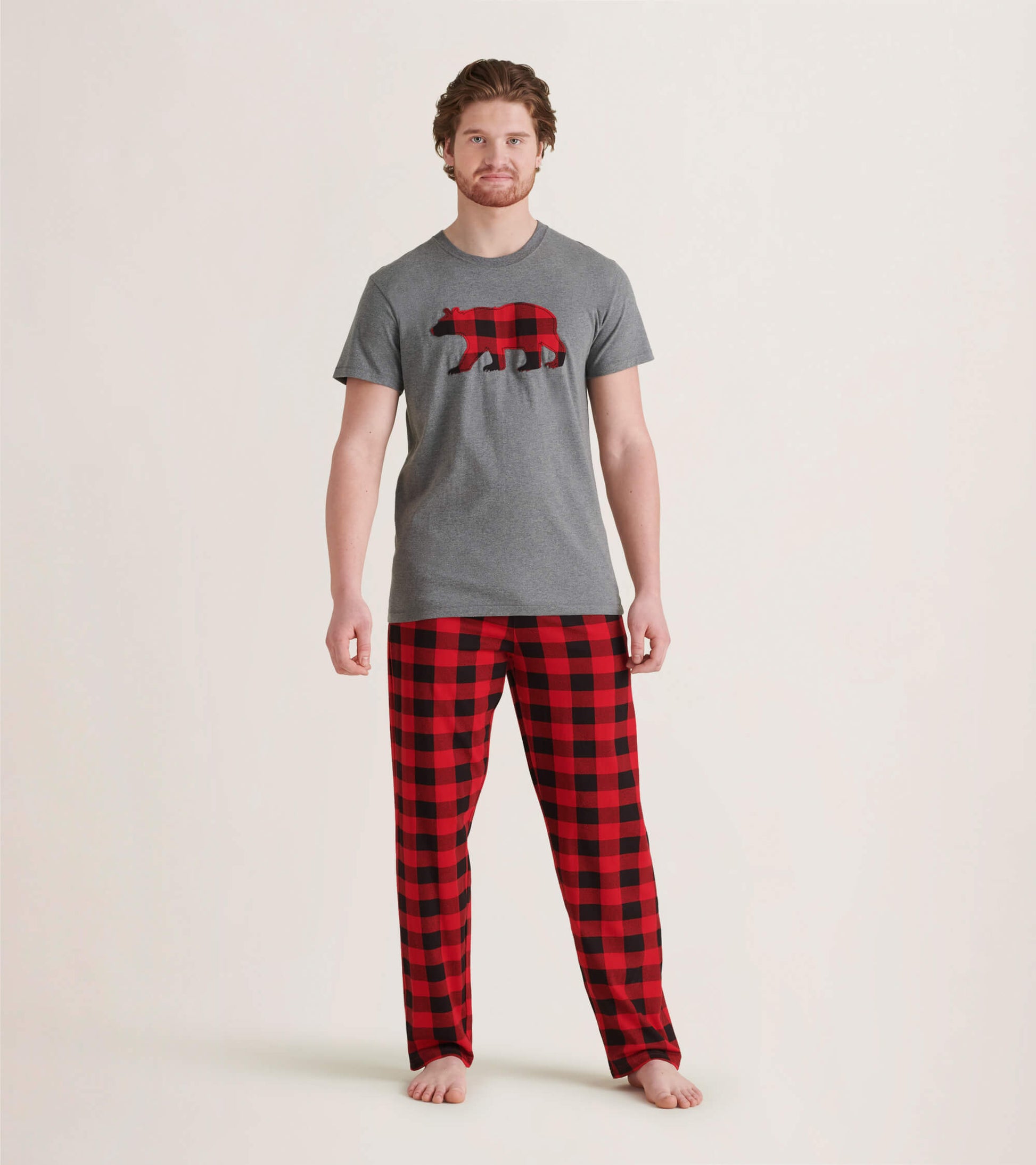 Men's pajama pants in red and black buffalo plaid pattern, made of stretch cotton, worn with a gray t-shirt.