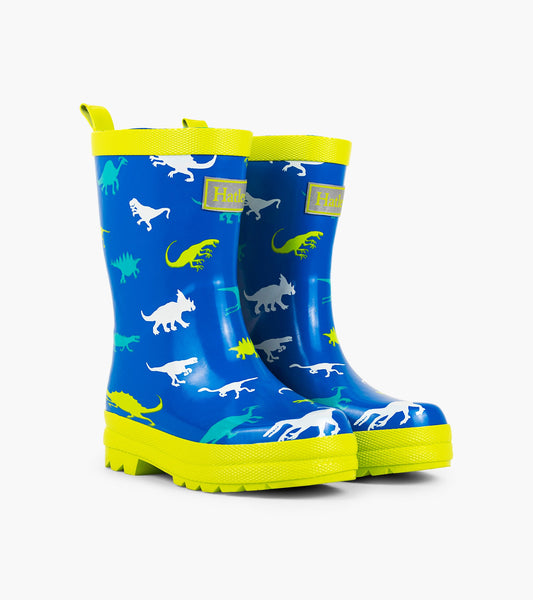 Blue rain boots featuring colorful dinosaur patterns and a bright yellow sole and trim. Ideal for kids' outdoor play.