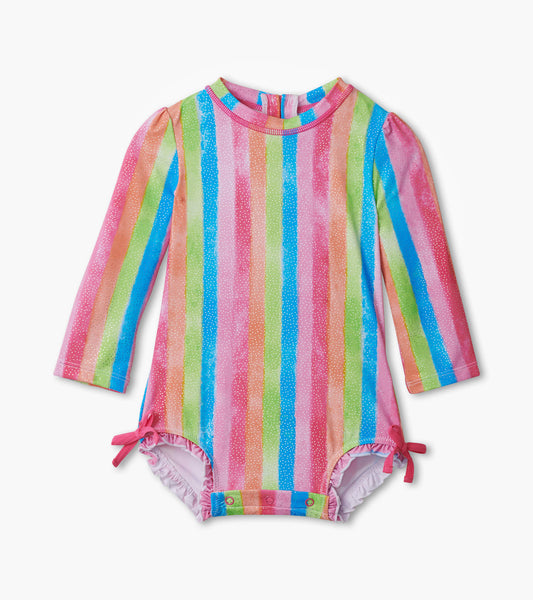 Long-sleeve rashguard swimsuit featuring colorful rainbow stripes and bow details at the legs, suitable for baby girls.