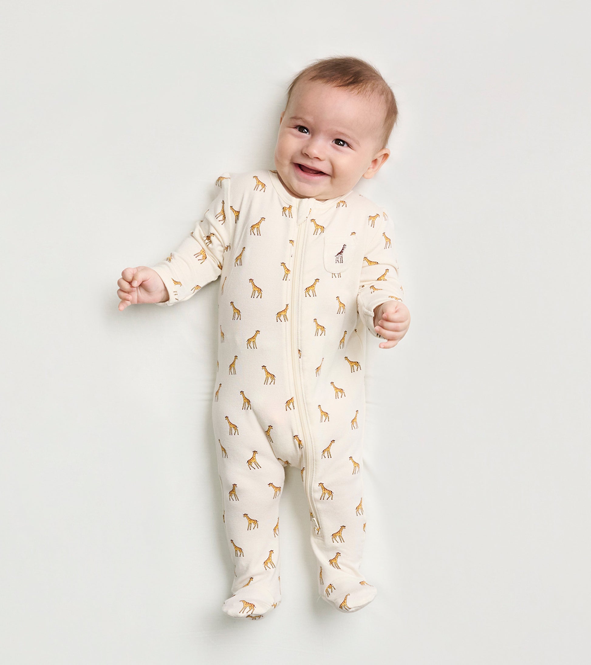 Cream footed sleeper for baby boys, featuring a playful giraffe print and a front zipper for easy dressing.