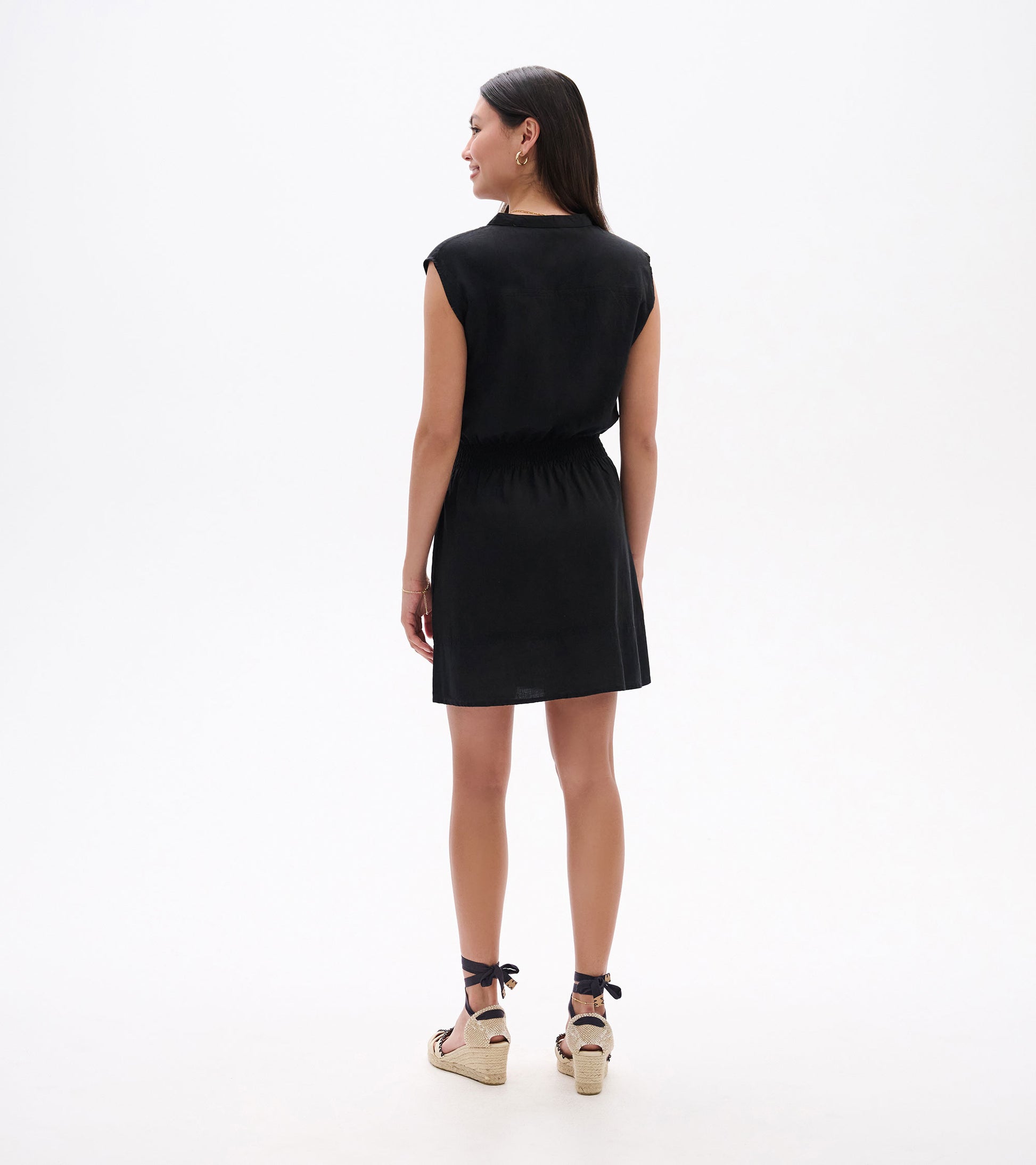 Black short-sleeve dress with an elastic waist, shown from the back, paired with espadrille sandals.