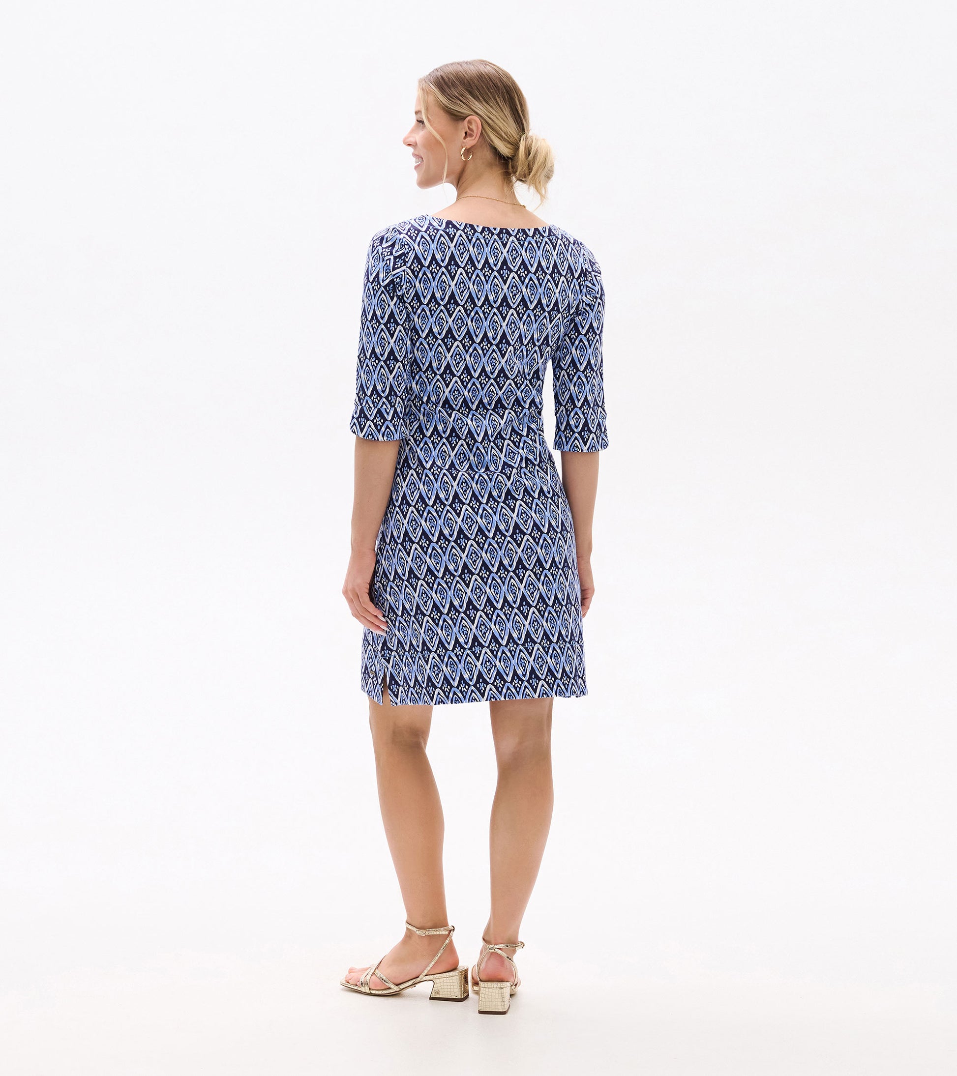 Back view of a blue dress featuring a painted diamond pattern and three-quarter sleeves, paired with strappy sandals.