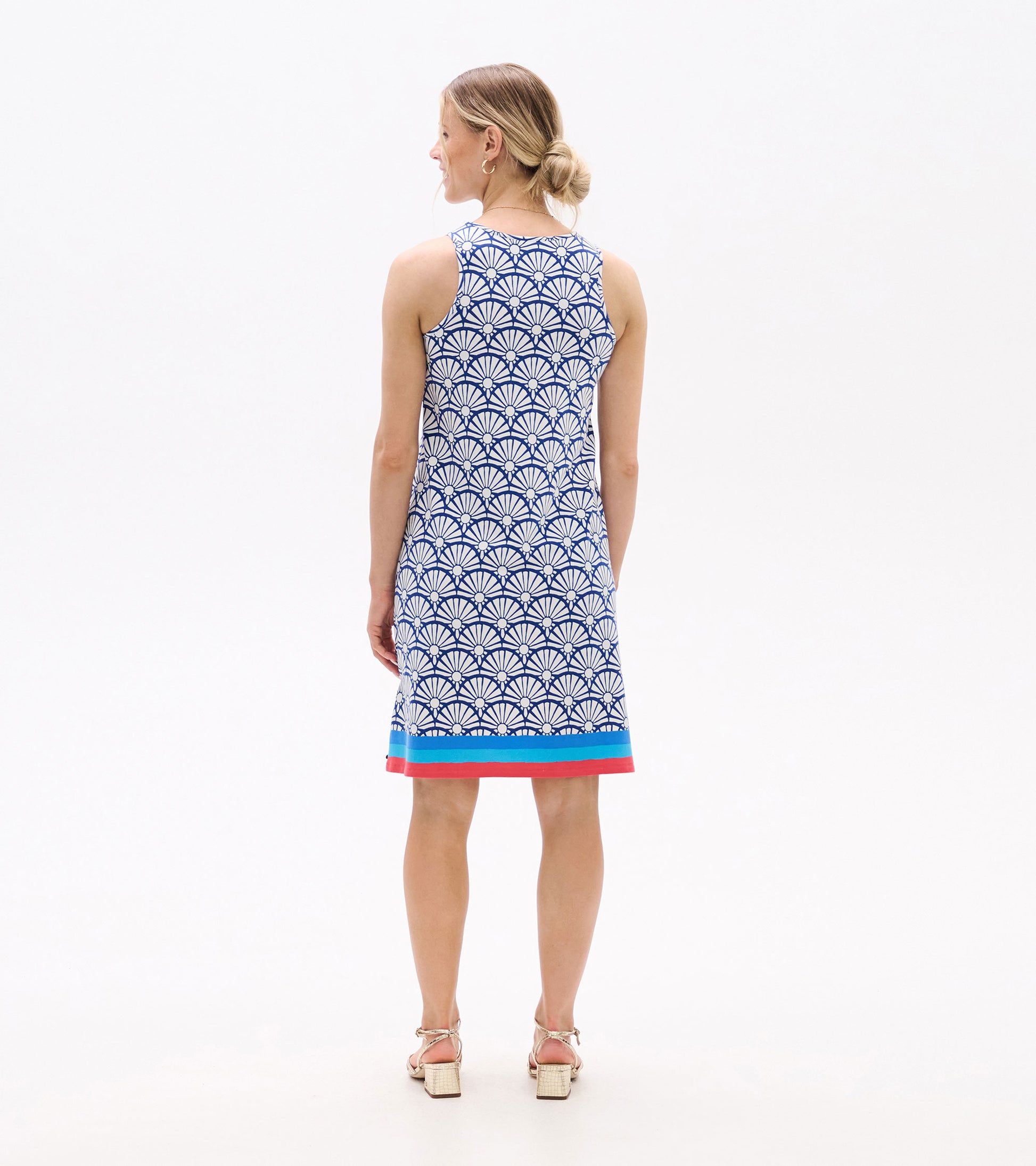 Sleeveless blue dress with a white shell pattern and colorful hem, shown from the back on a model.