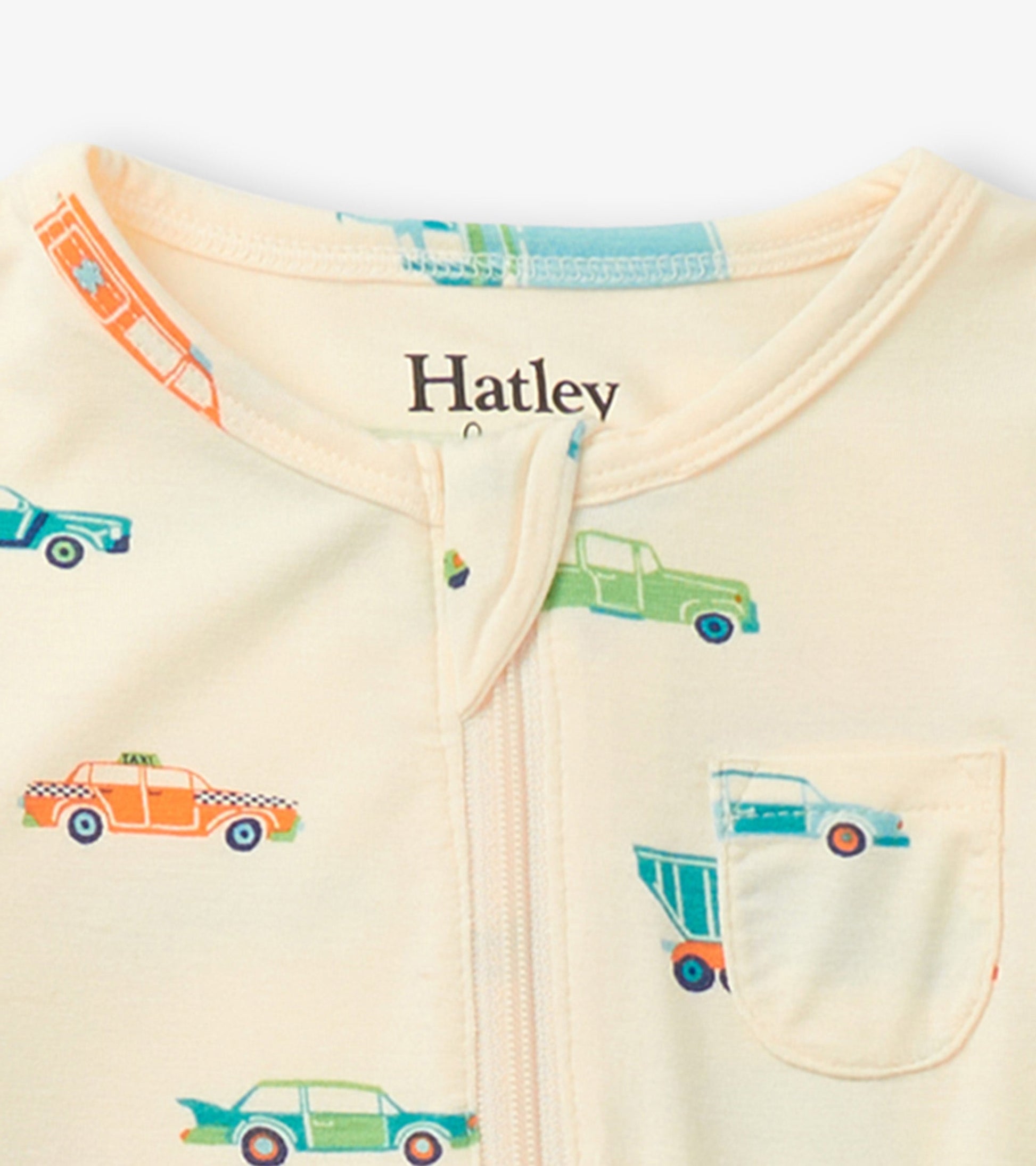 Cream footed sleeper featuring colorful car prints and a front zipper, designed for baby boys.