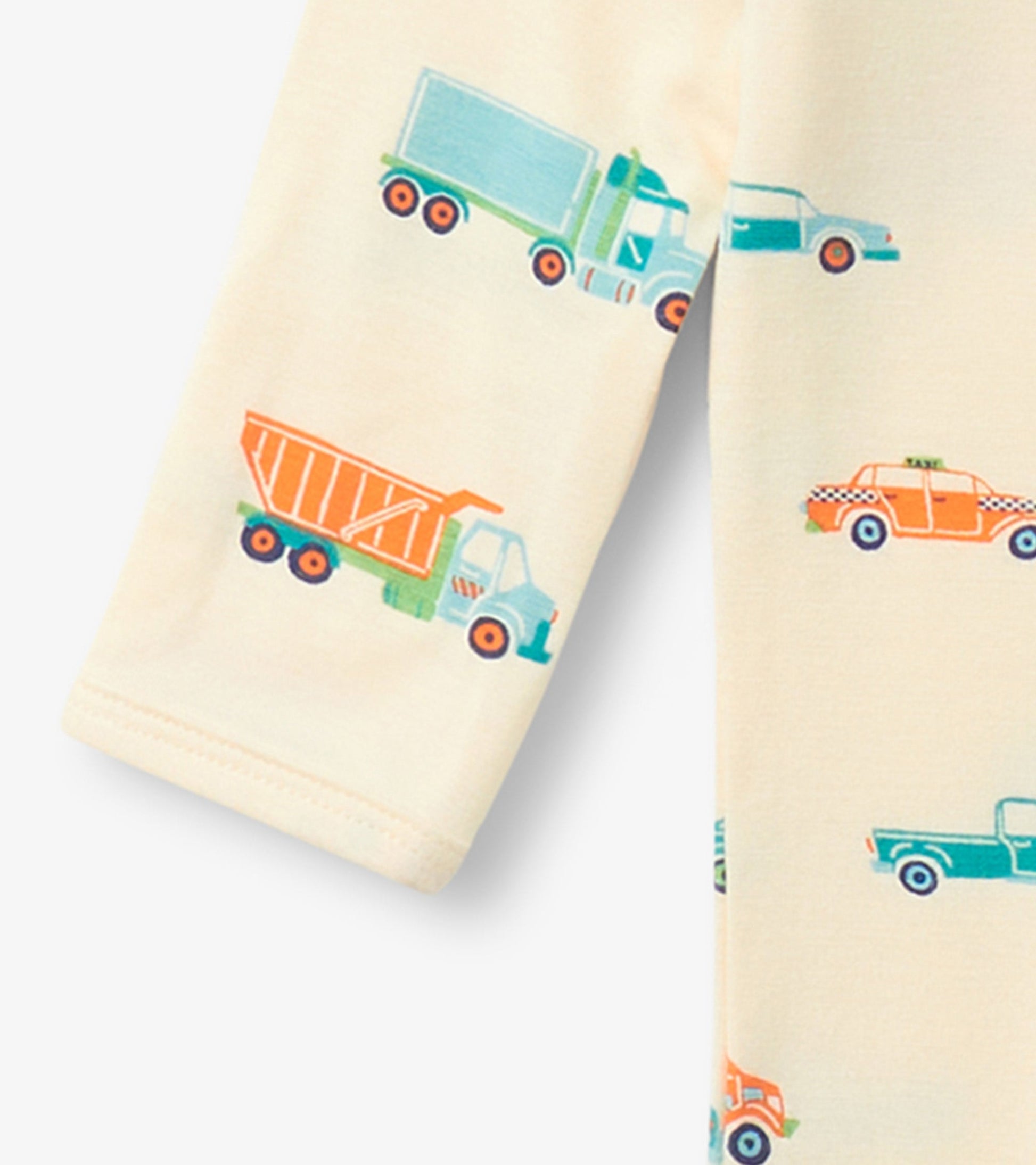 Cream footed sleeper featuring colorful truck and car prints, ideal for baby boys.