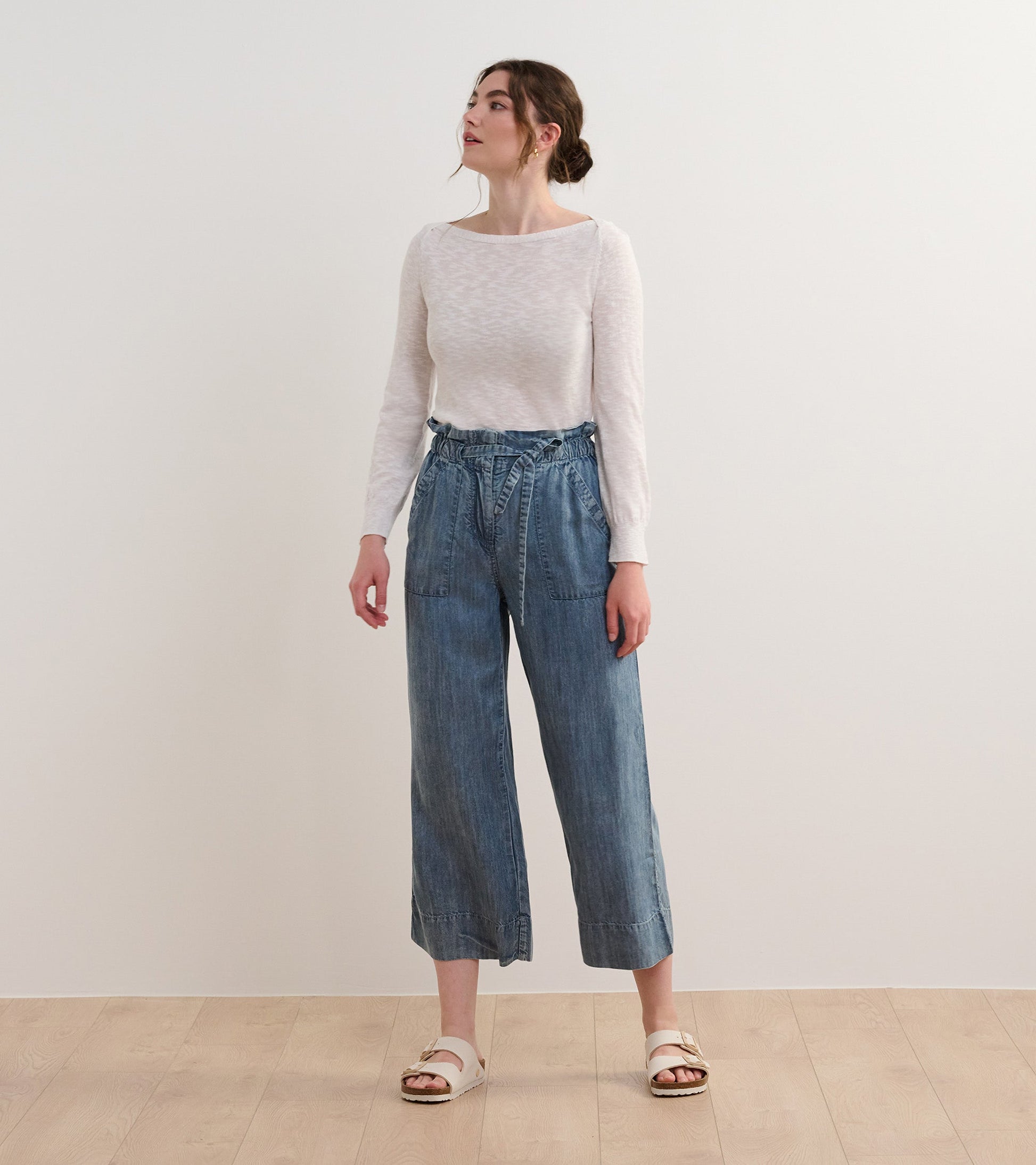 White 3/4 sleeve knit Breton top, featuring a relaxed fit, paired with high-waisted denim trousers and sandals.