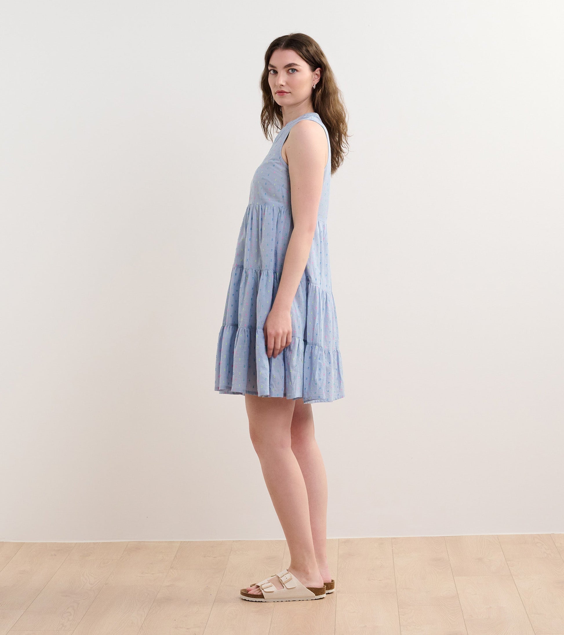 Light blue chambray dress with a tiered design and colorful spots, featuring a sleeveless cut and relaxed fit.