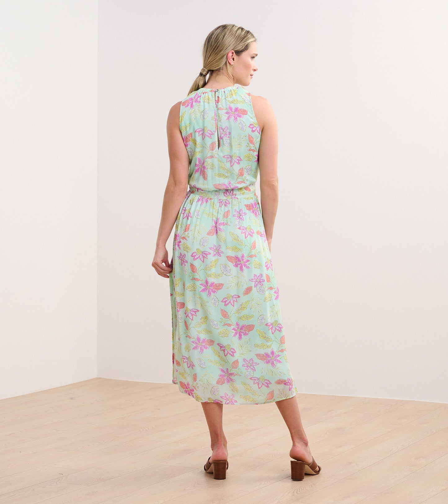 Back view of a sleeveless, mint green column dress with a distressed floral pattern in pink and yellow.