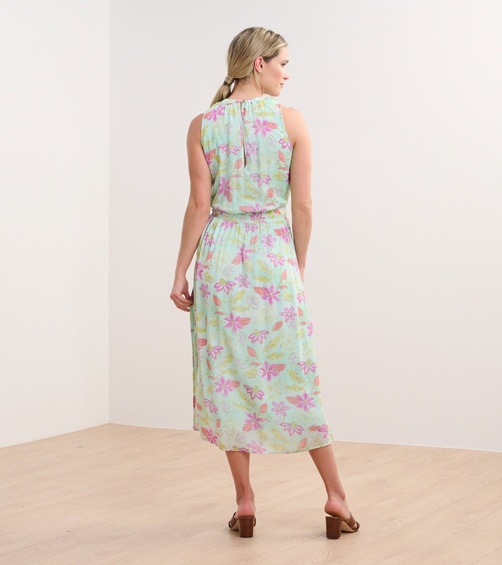 Back view of a sleeveless, mint green column dress with a distressed floral pattern in pink and yellow.