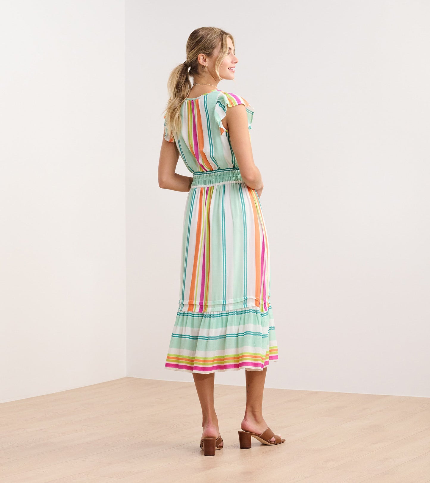 Lightweight midi dress in sea glass stripes with ruffled sleeves and a smocked waist, shown from the back.