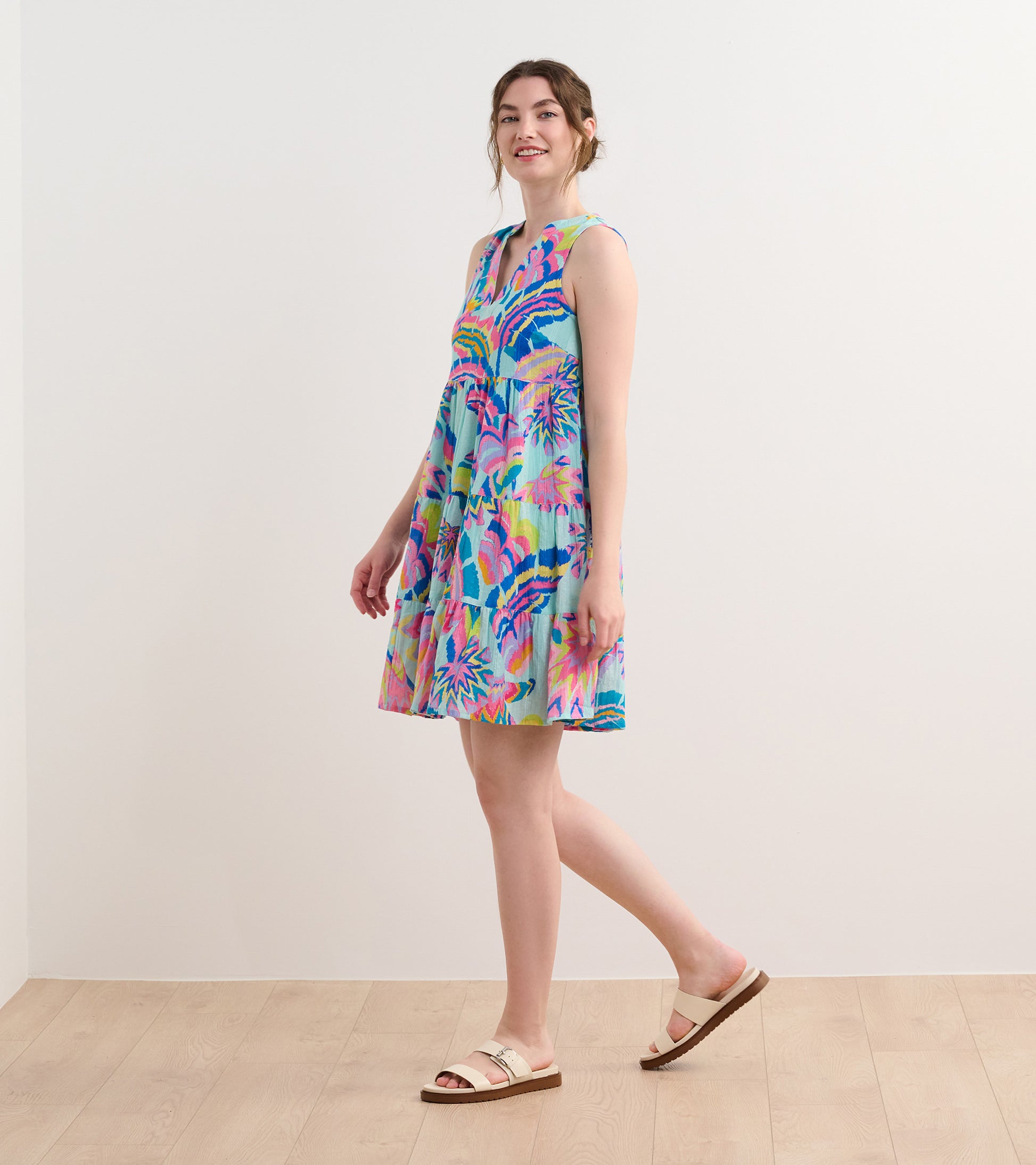 Sleeveless dress in light blue with vibrant palm leaf print, flared silhouette, and knee-length design.