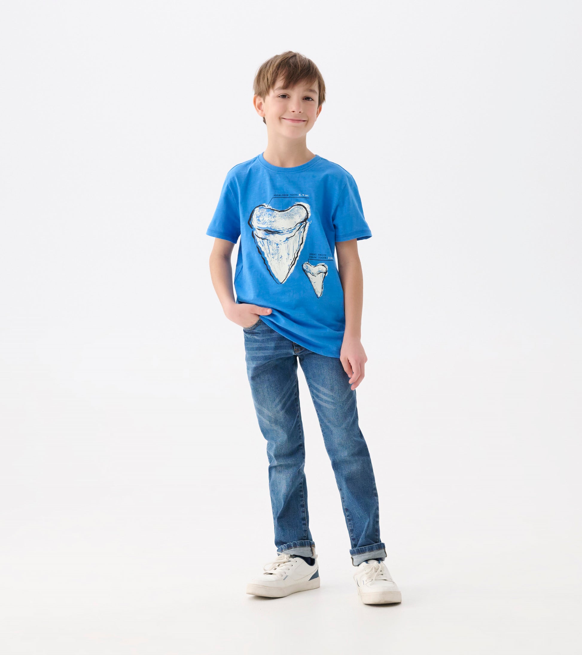 Blue graphic tee featuring shark tooth prints, short sleeves, and a relaxed fit, worn by a boy with jeans.