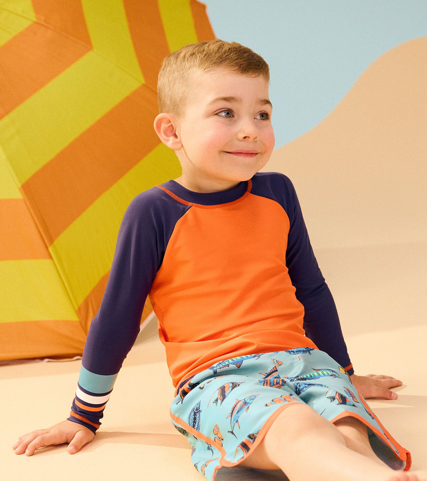 Boys' long sleeve rashguard in bright orange with navy sleeves, perfect for beach or pool activities.