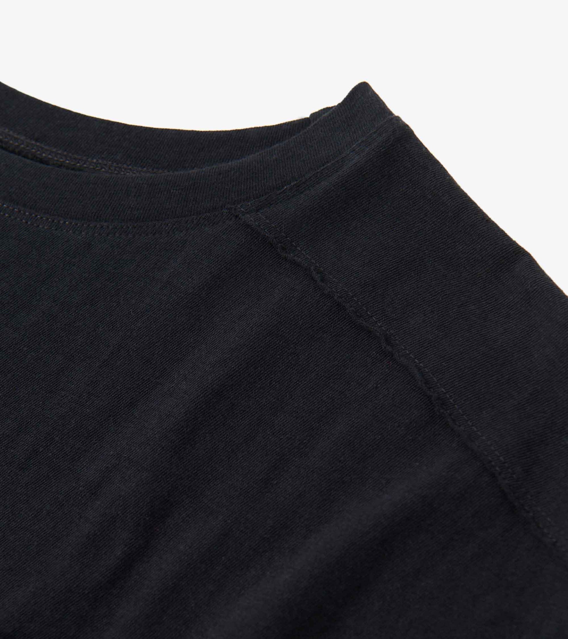 Black slouchy pocket tee with a relaxed fit and soft fabric, featuring a round neckline and visible stitching details.