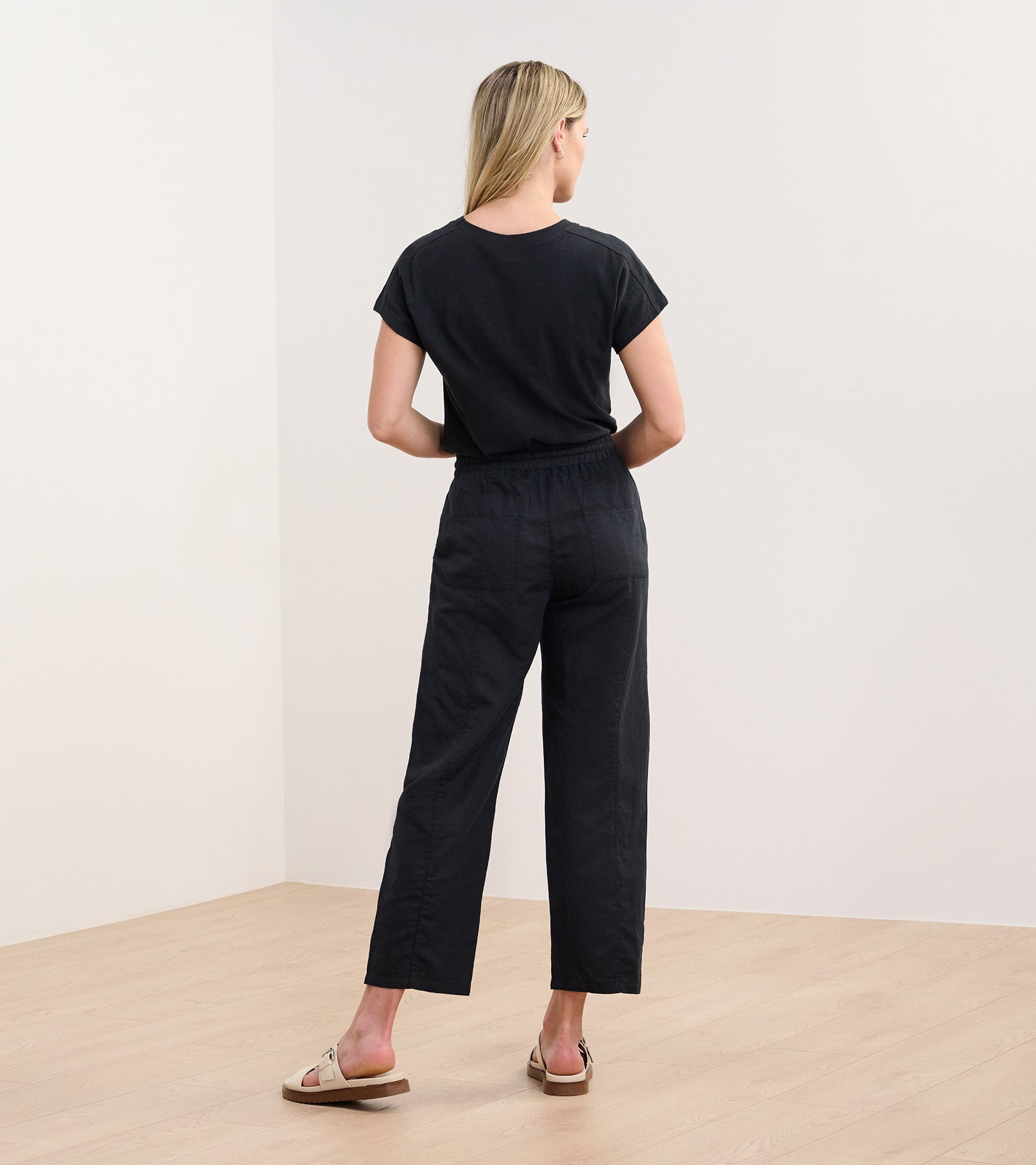 Black straight leg linen pants with an elastic waistband, shown from the back on a model.