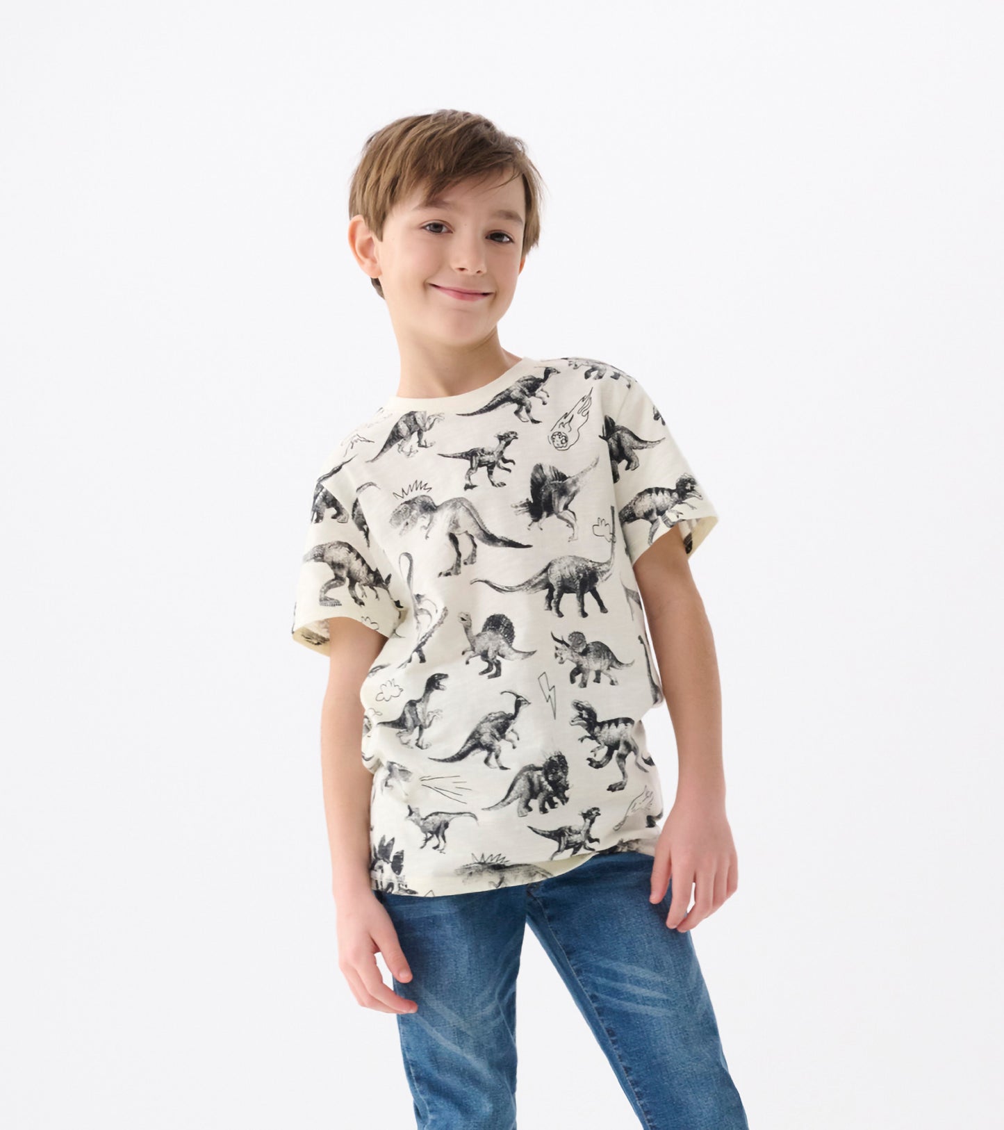 Cream-colored graphic tee featuring various dinosaur illustrations, short sleeves, and a relaxed fit.