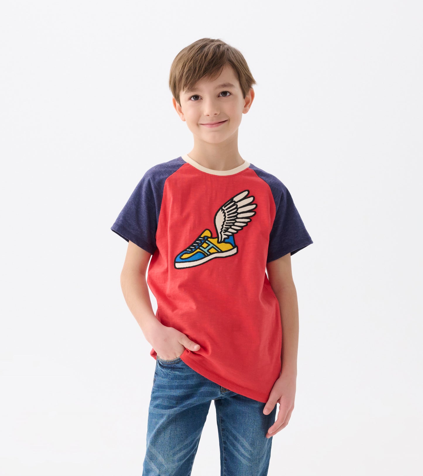 Red and navy raglan t-shirt featuring a colorful winged sneaker graphic, worn by a smiling boy.