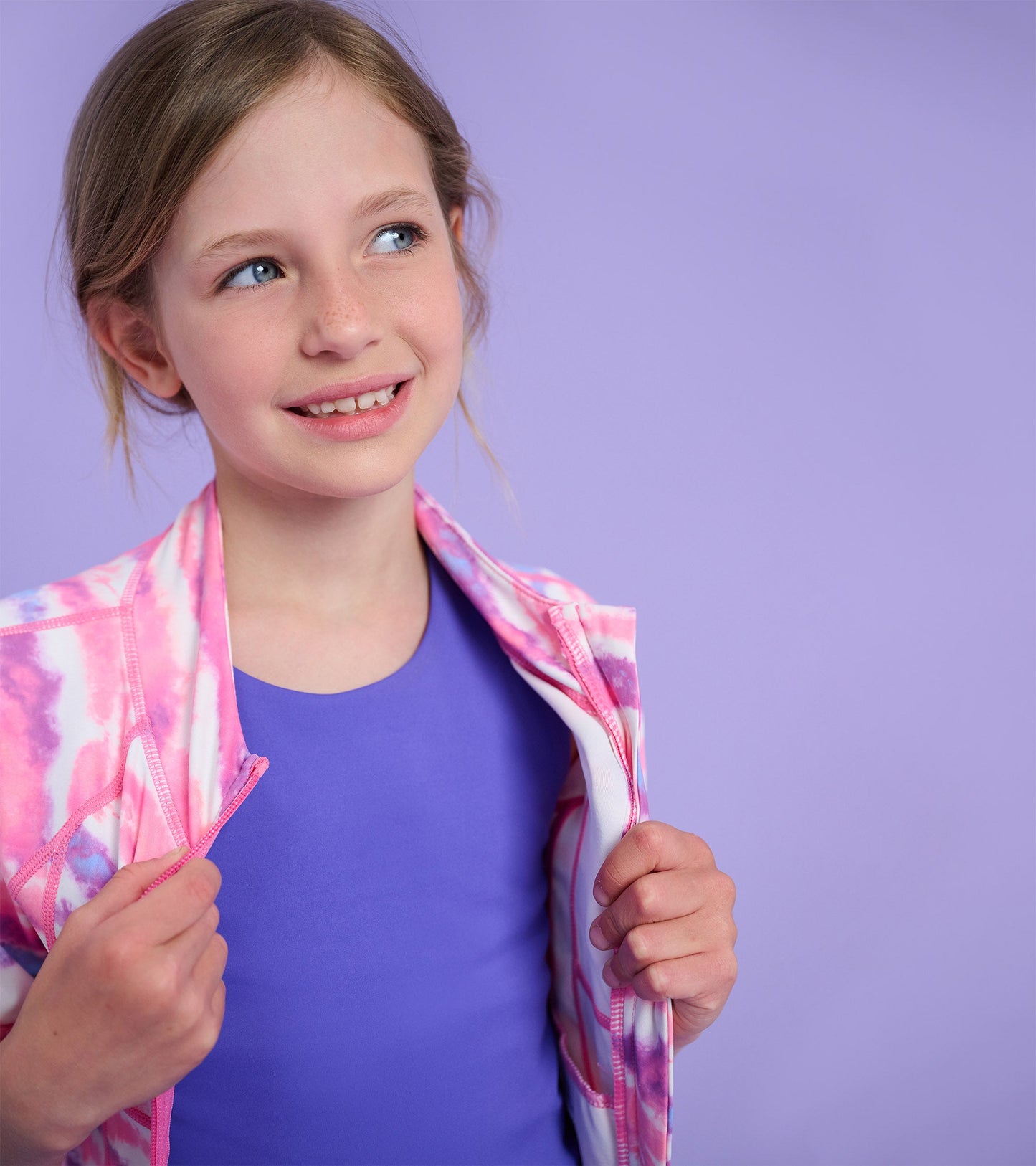 Ombre active jacket in pink and white, featuring a zip front, worn over a purple top, suitable for active wear.