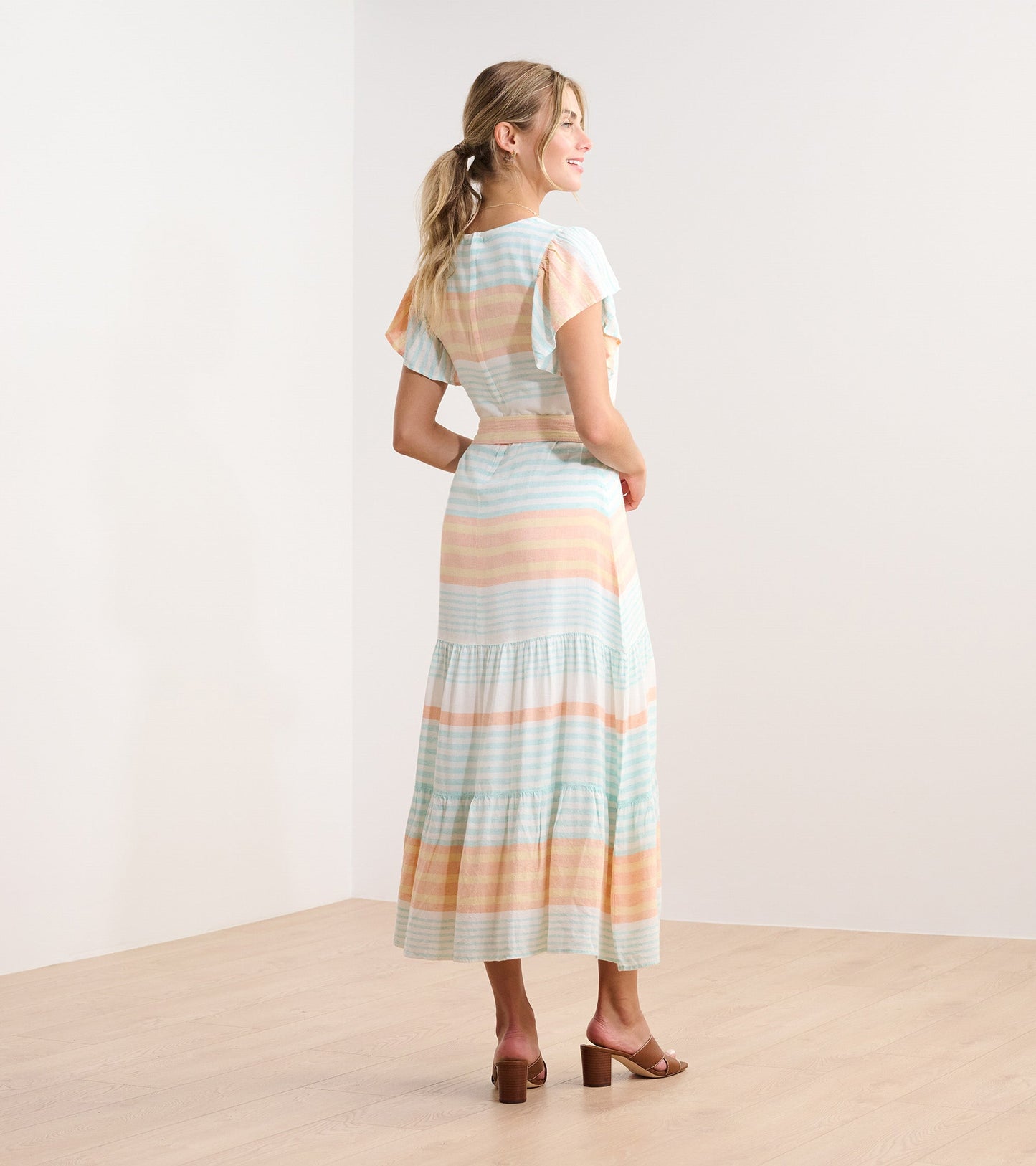 Pastel striped maxi dress with flutter sleeves and tiered skirt, shown from the back.