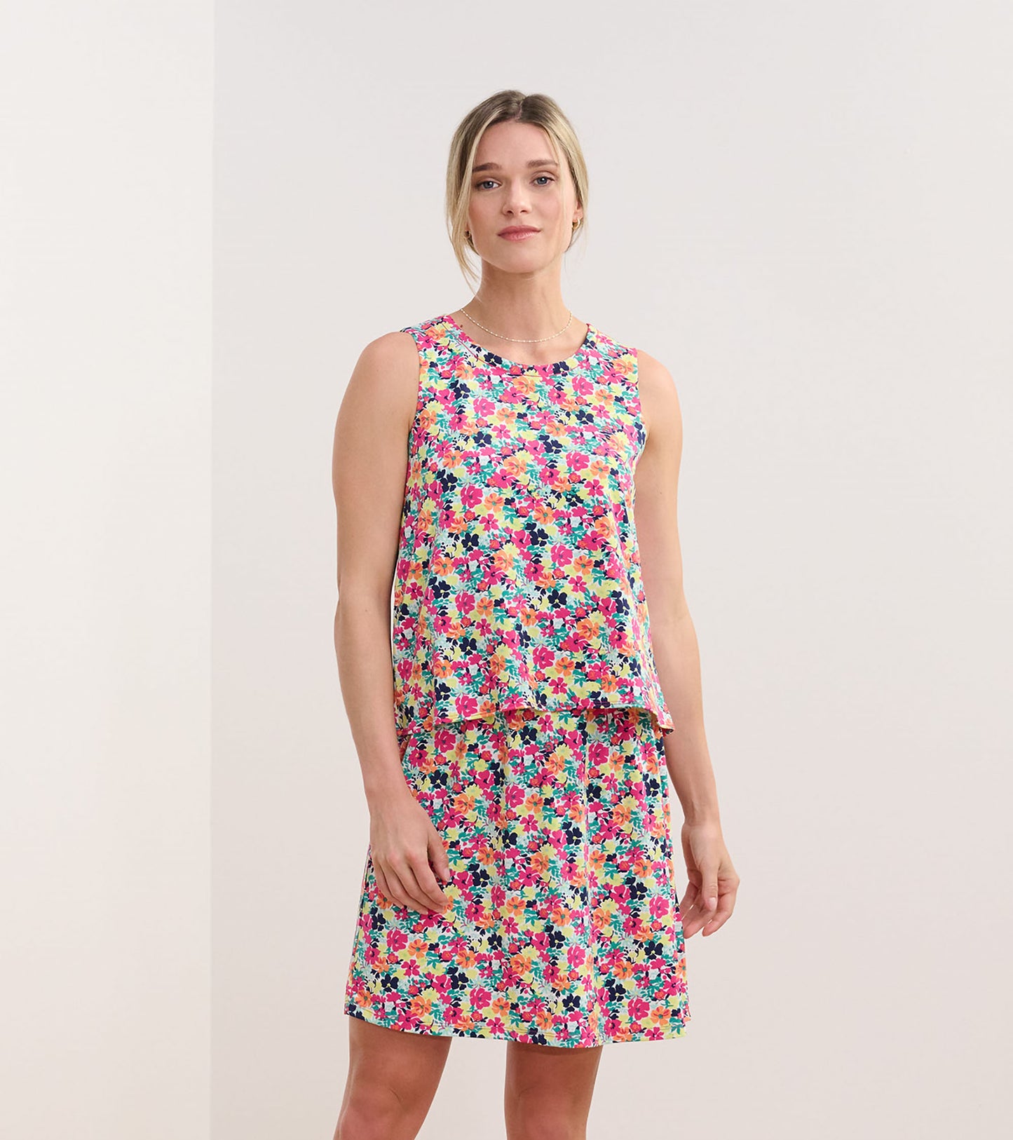 Sleeveless dress featuring a vibrant floral pattern in pink, yellow, and blue, with a relaxed fit and flared skirt.