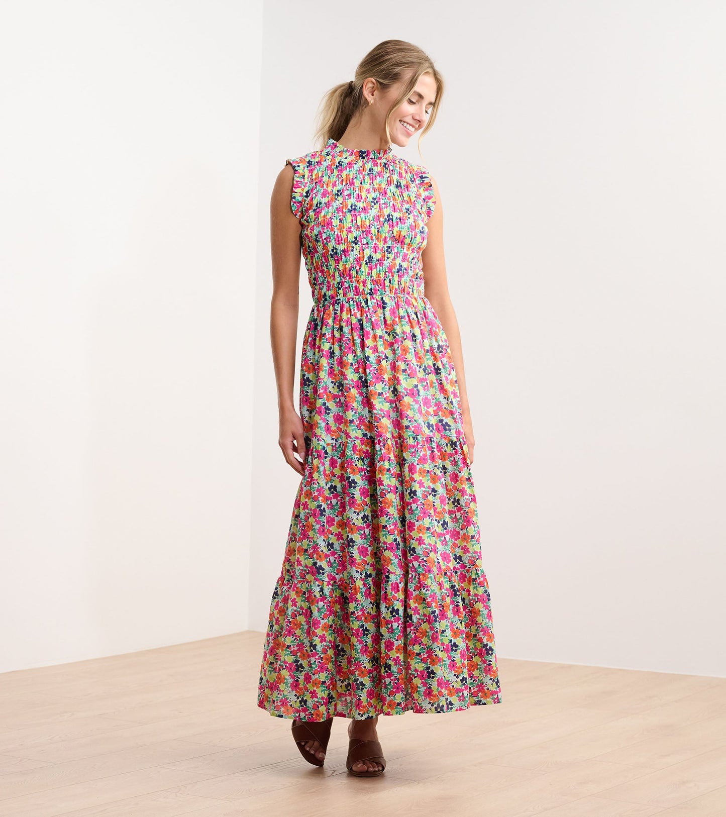 Floral smocked maxi dress with a high neckline and ruffled sleeves, featuring vibrant pink, green, and blue patterns.