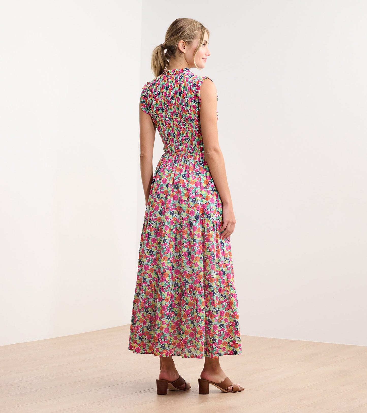 Back view of a smocked maxi dress featuring a vibrant floral pattern in pink, purple, and green hues.