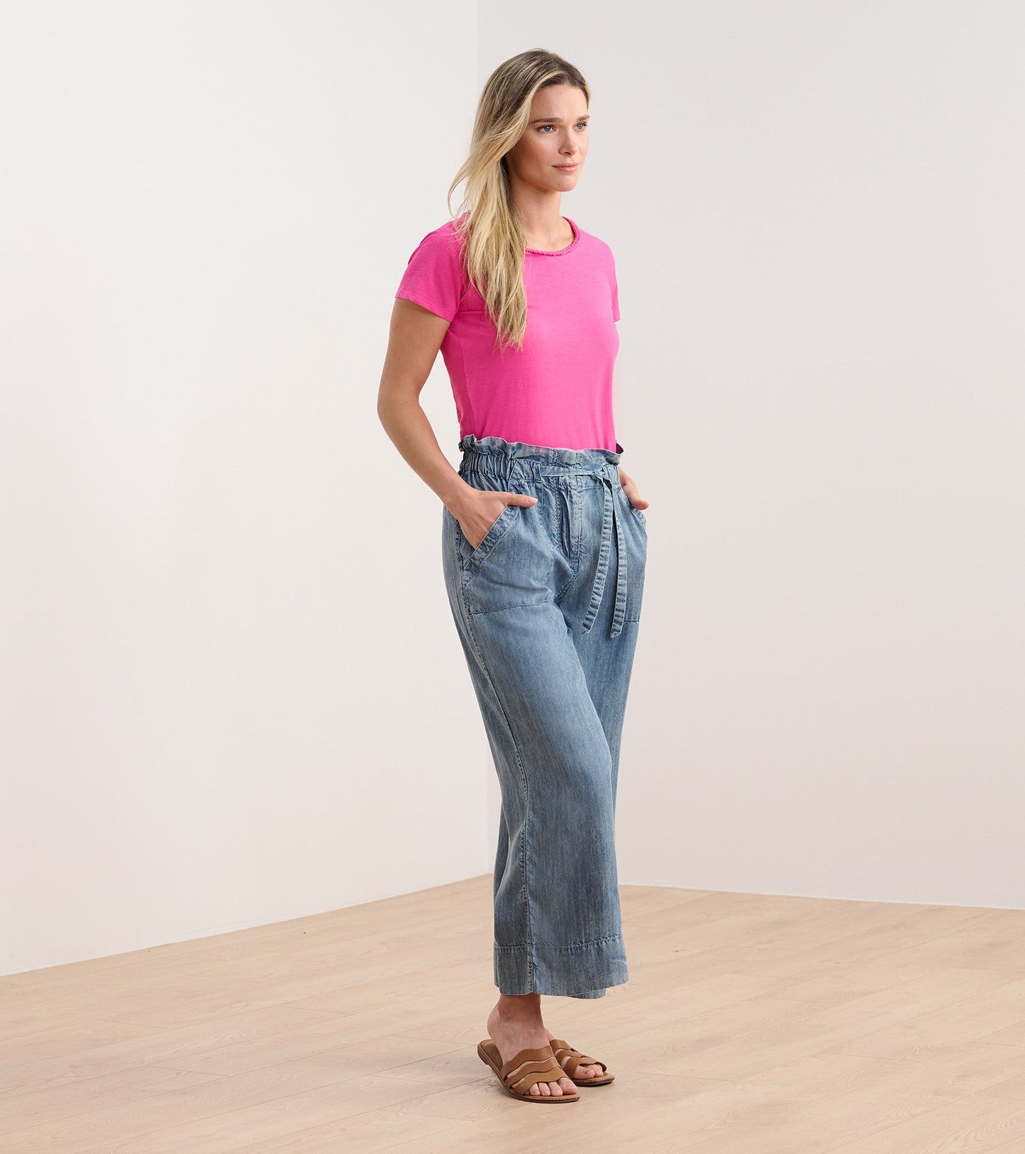 Fuschia braided neck tee paired with light blue wide-leg pants, model standing with hands in pockets.