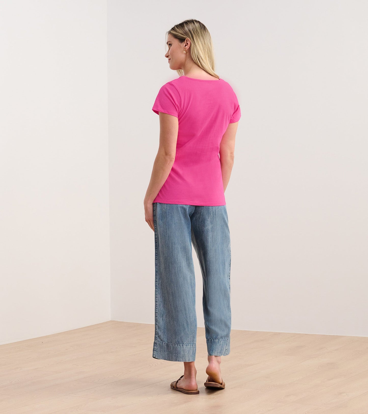 Fuschia braided neck tee worn with light blue wide-leg jeans, viewed from the back.