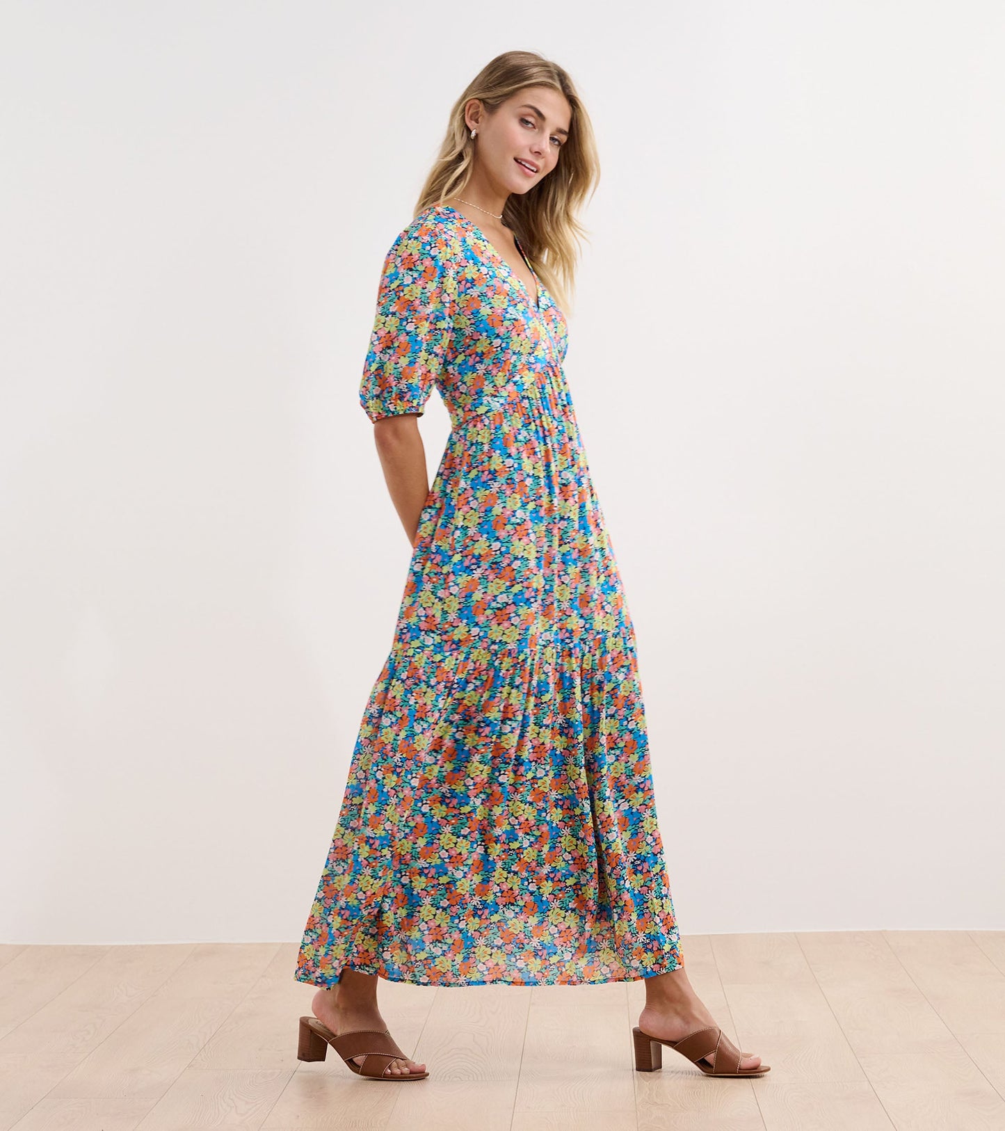 Maxi dress featuring a vibrant floral pattern in blue, pink, and green, with short puff sleeves and a flattering silhouette.